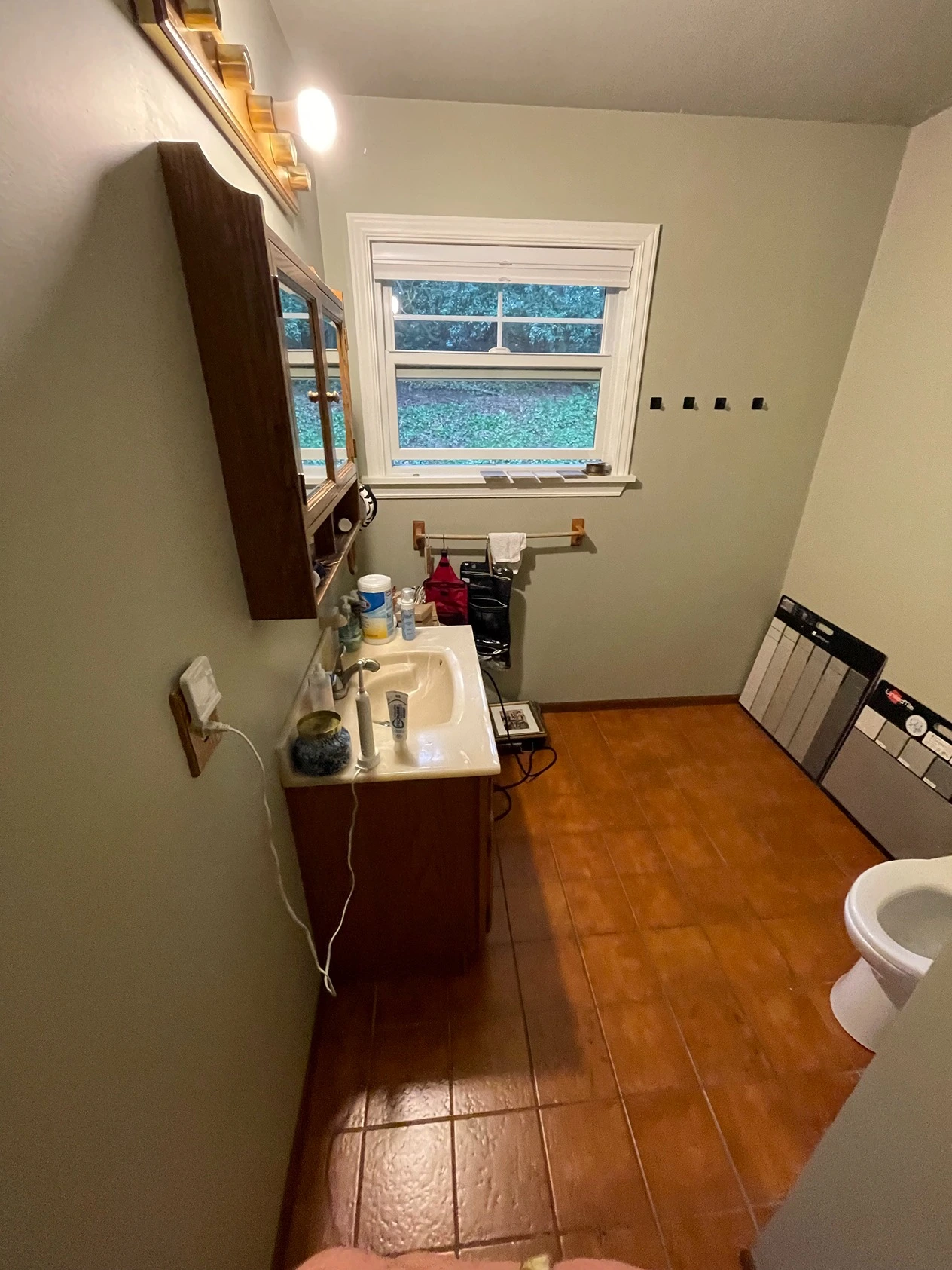 Small outdated bathroom with worn tiles and dim lighting