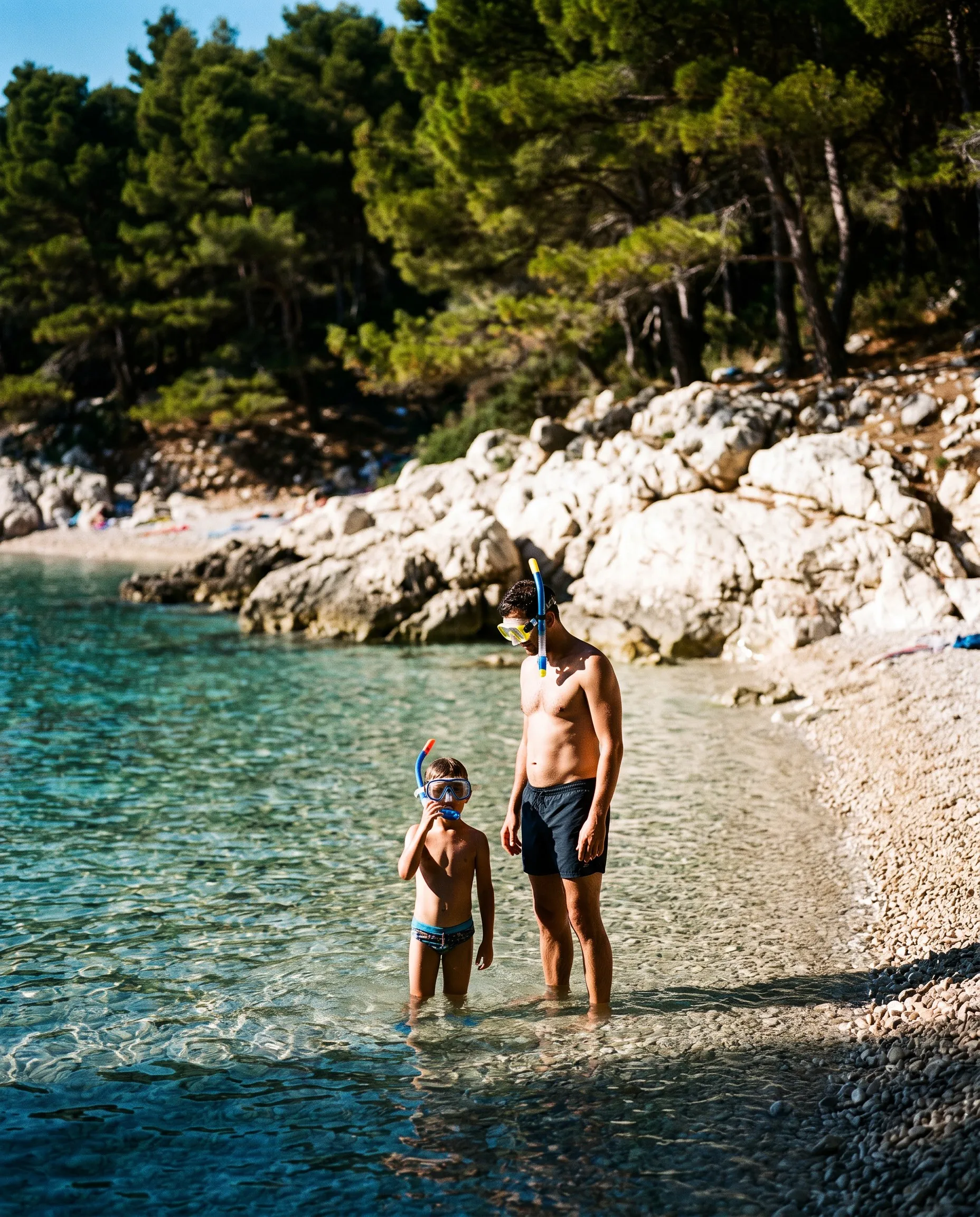 Kind met snorkelmasker in het heldere water van een kiezelstrand in Kroatië