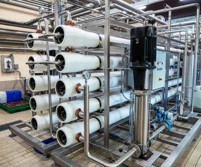 A large-scale industrial reverse osmosis water filtration system with multiple membrane housings, pumps, and extensive stainless steel piping, suggesting a commercial water treatment facility.