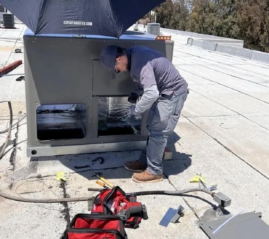 Technician performing spring AC maintenance in a sunny backyard with blooming flowers