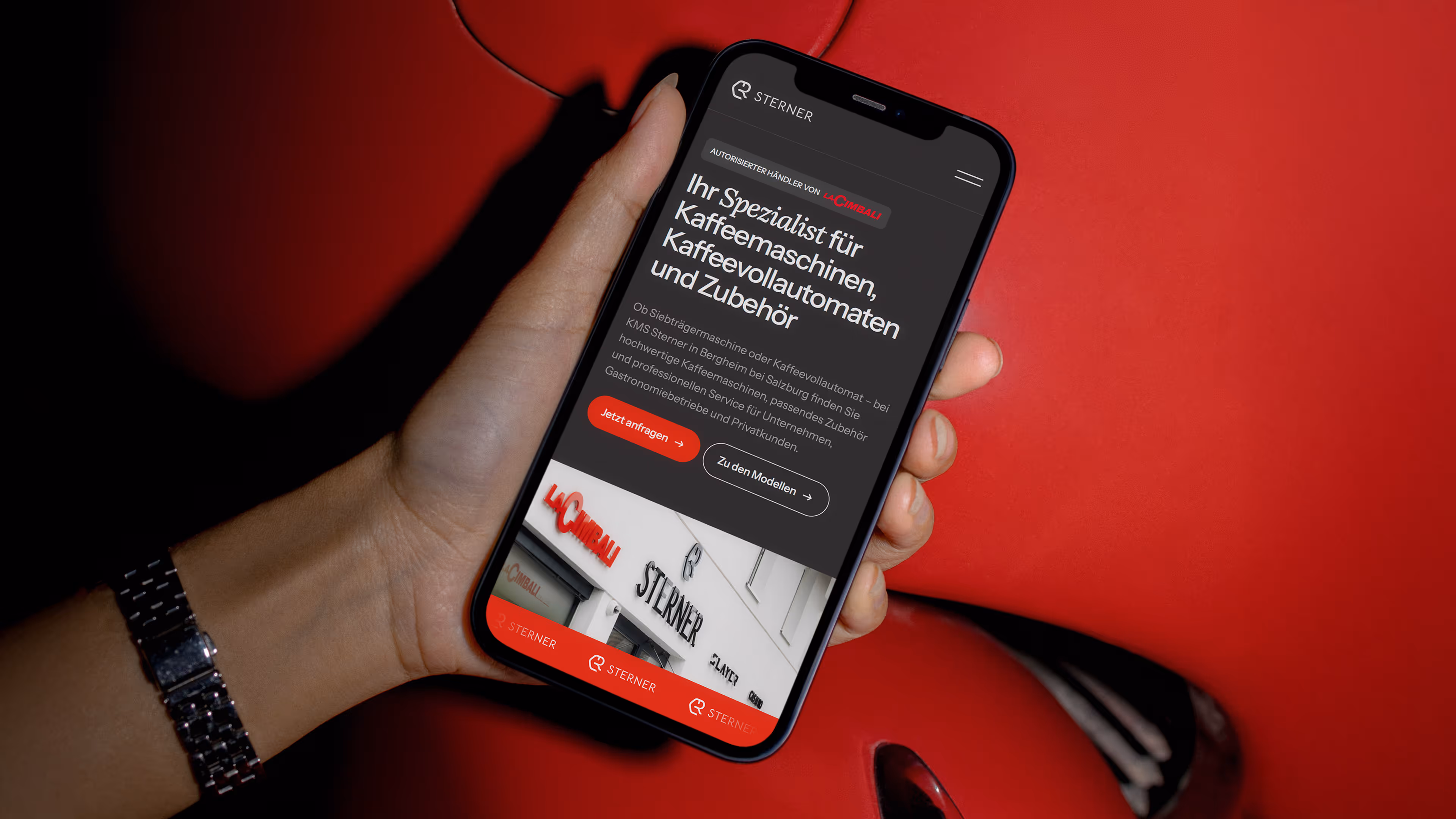 Hand hält Smartphone mit Webseite von Sterner, Spezialist für Kaffeemaschinen, Kaffeevollautomaten und Zubehör.