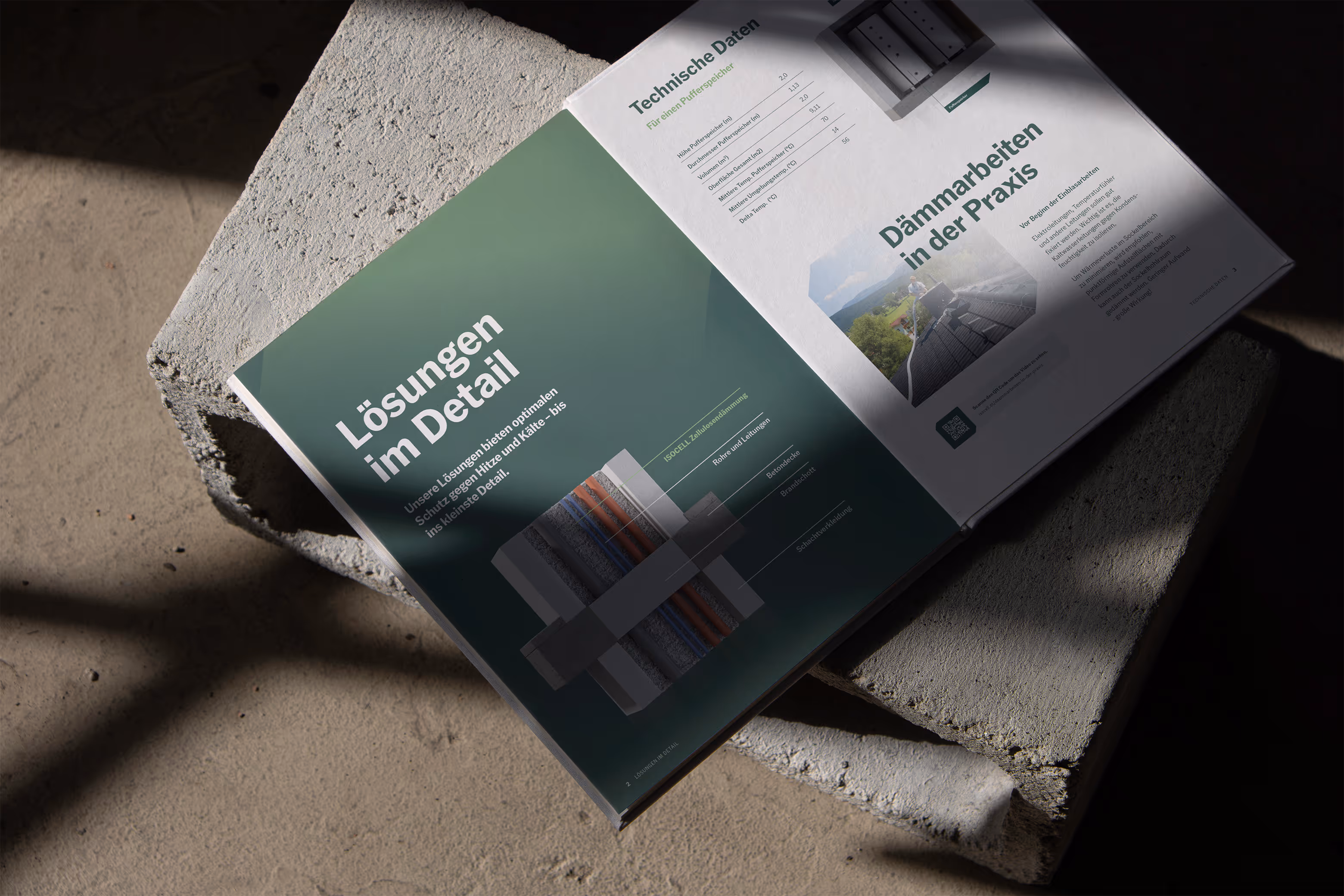 Geöffnetes Buch mit technischen Details und Illustrationen zur Isolierung, liegend auf Betonsteinen unter natürlichem Licht.