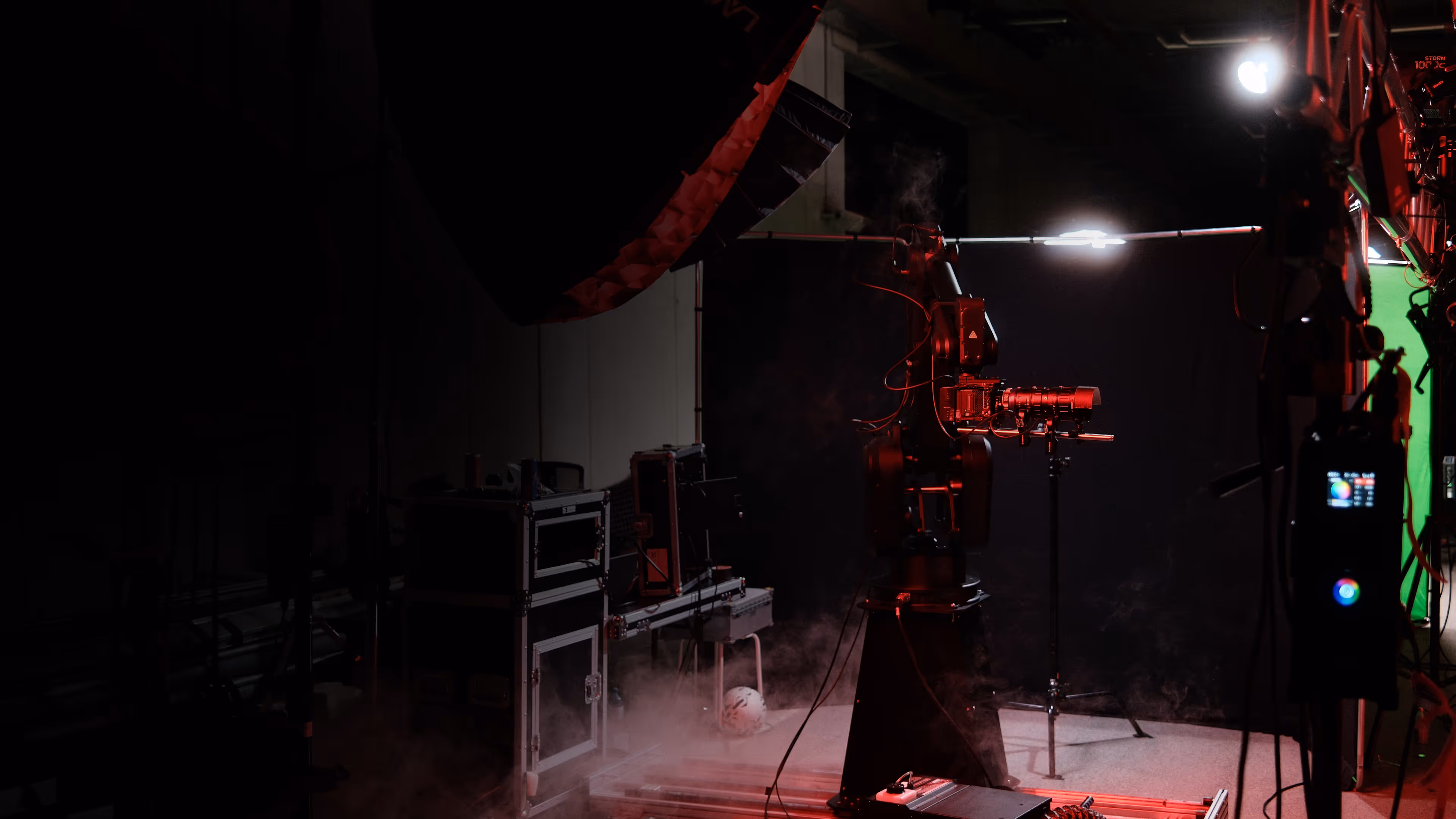 Dunkles Filmstudio mit Roboterarm, der eine Kamera hält, und Nebel auf dem Boden.