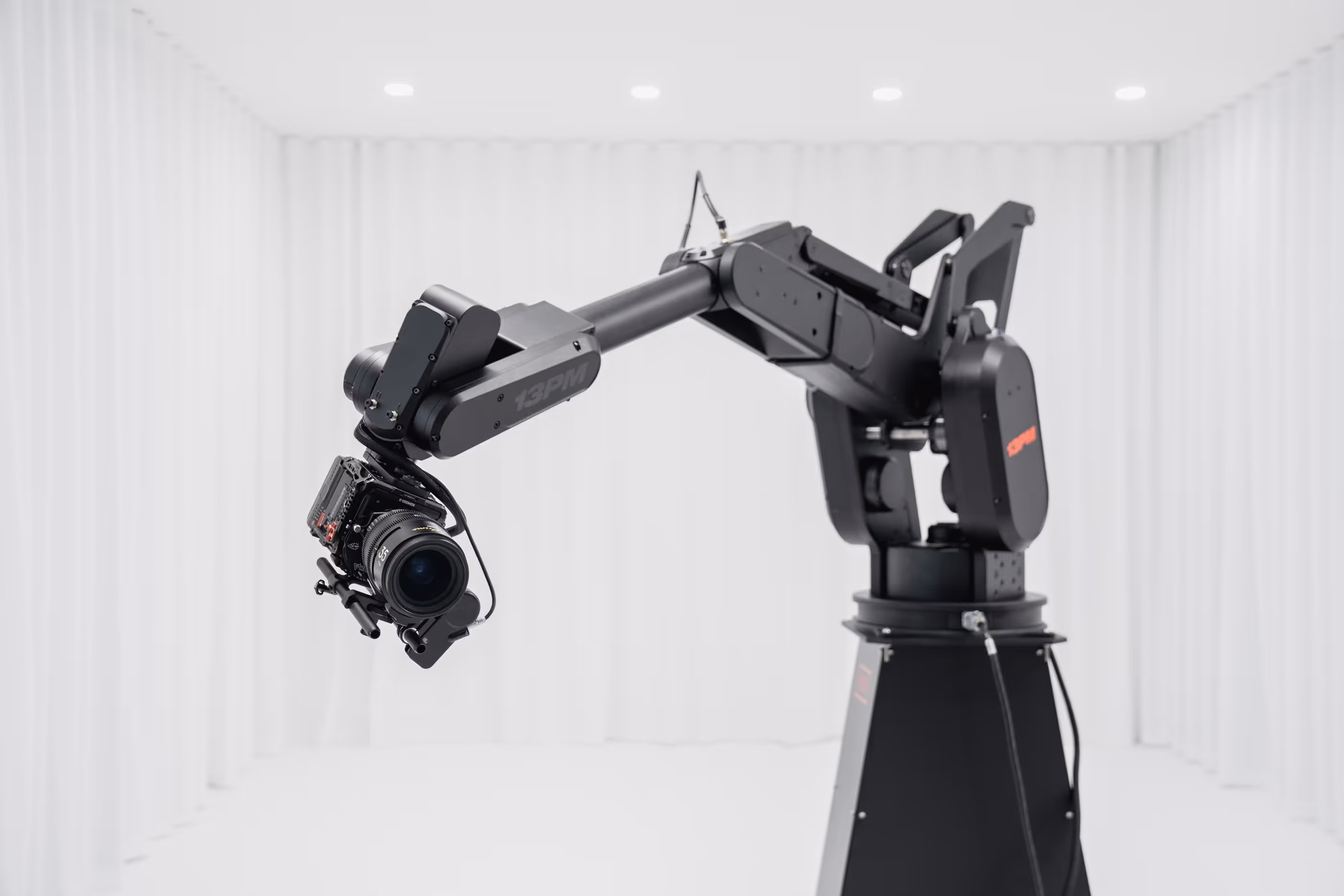 Schwarzer Kameraroboterarm mit Linse in weißem Raum mit Vorhängen.