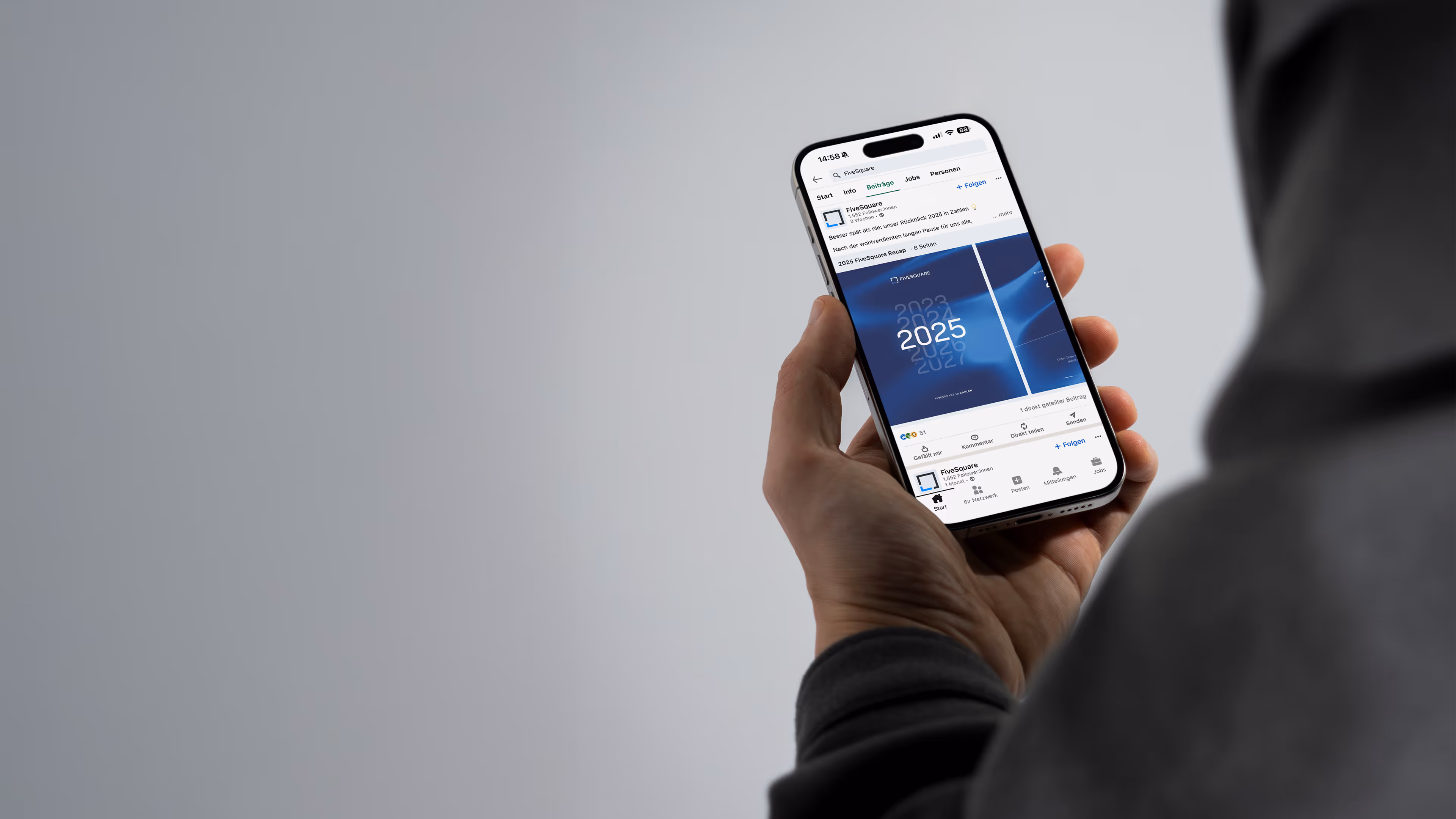 Hand hält ein Smartphone mit einem LinkedIn-Beitrag von FiveSquare zur Jahresvorschau 2025.