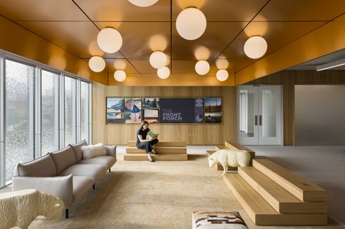 A woman reading a book in the lobby of a workplace. 