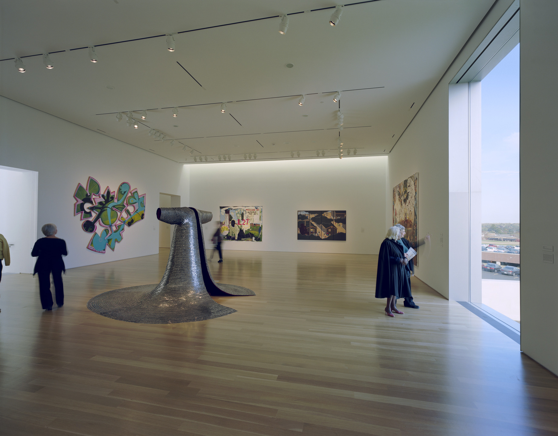 A high-ceilinged gallery features wall paintings and a sculptural robe as the centerpiece.
