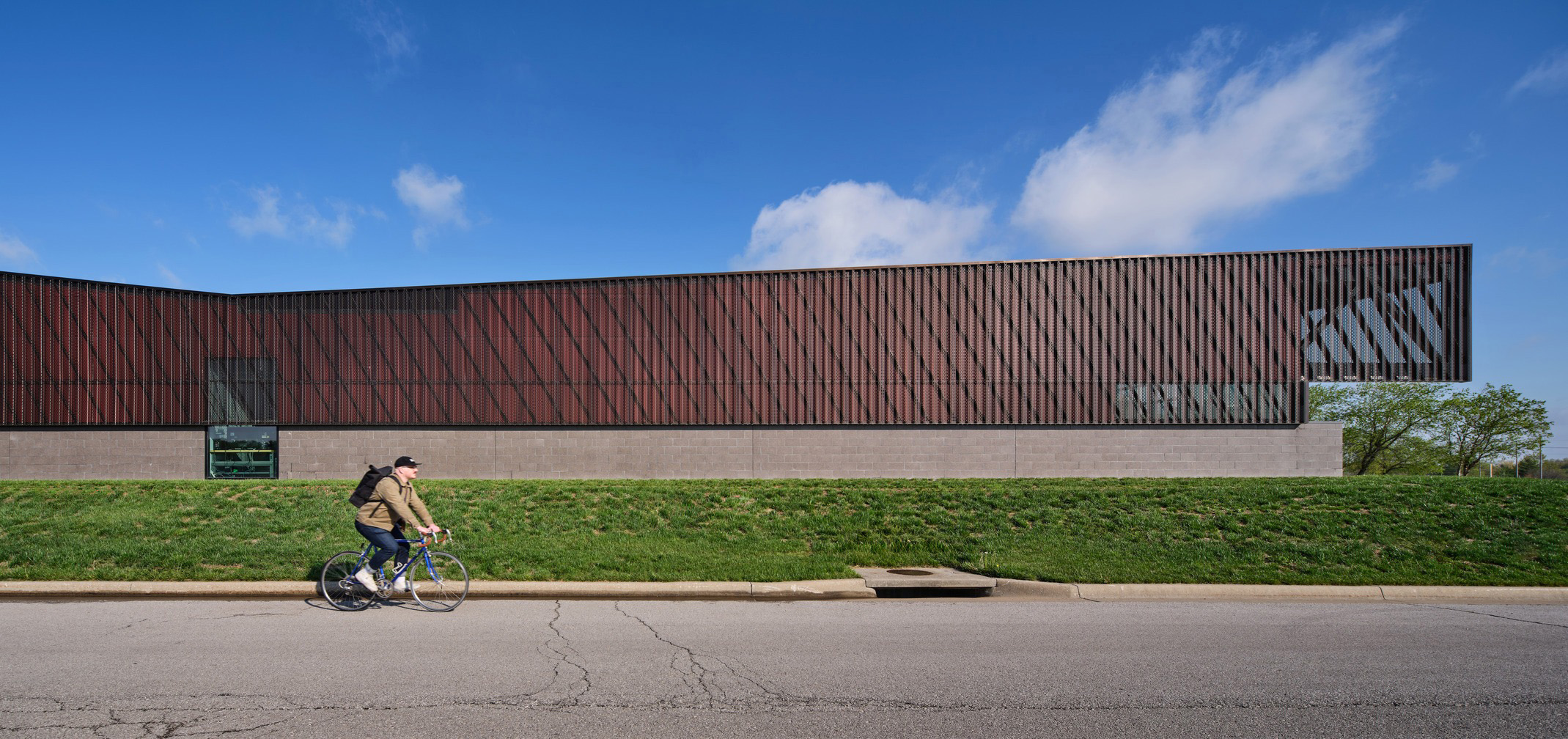 An aluminum scrim surrounds an angular stone and glass building.