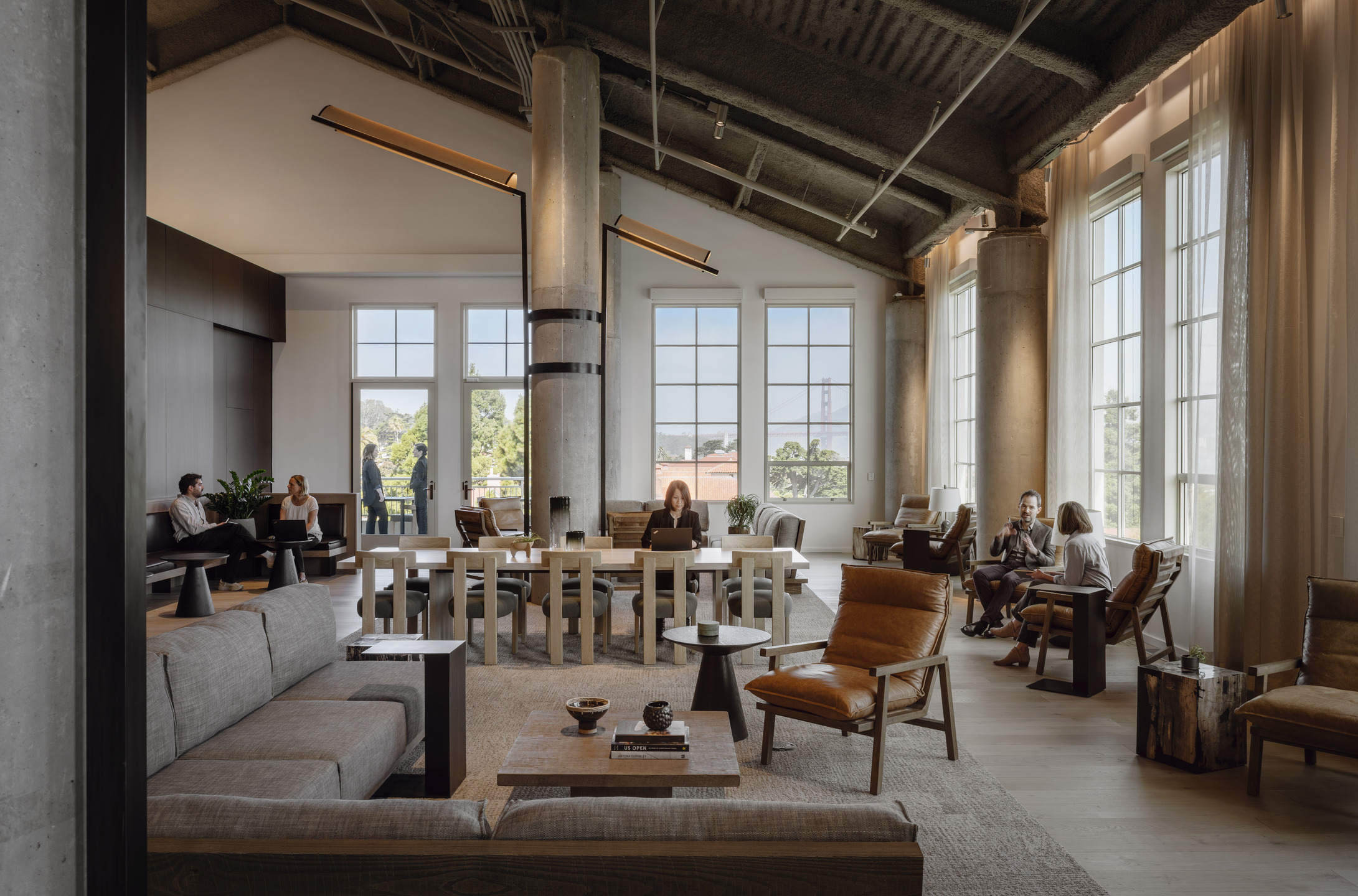Tall windows and industrial finishes accent an open-air co-working space. 