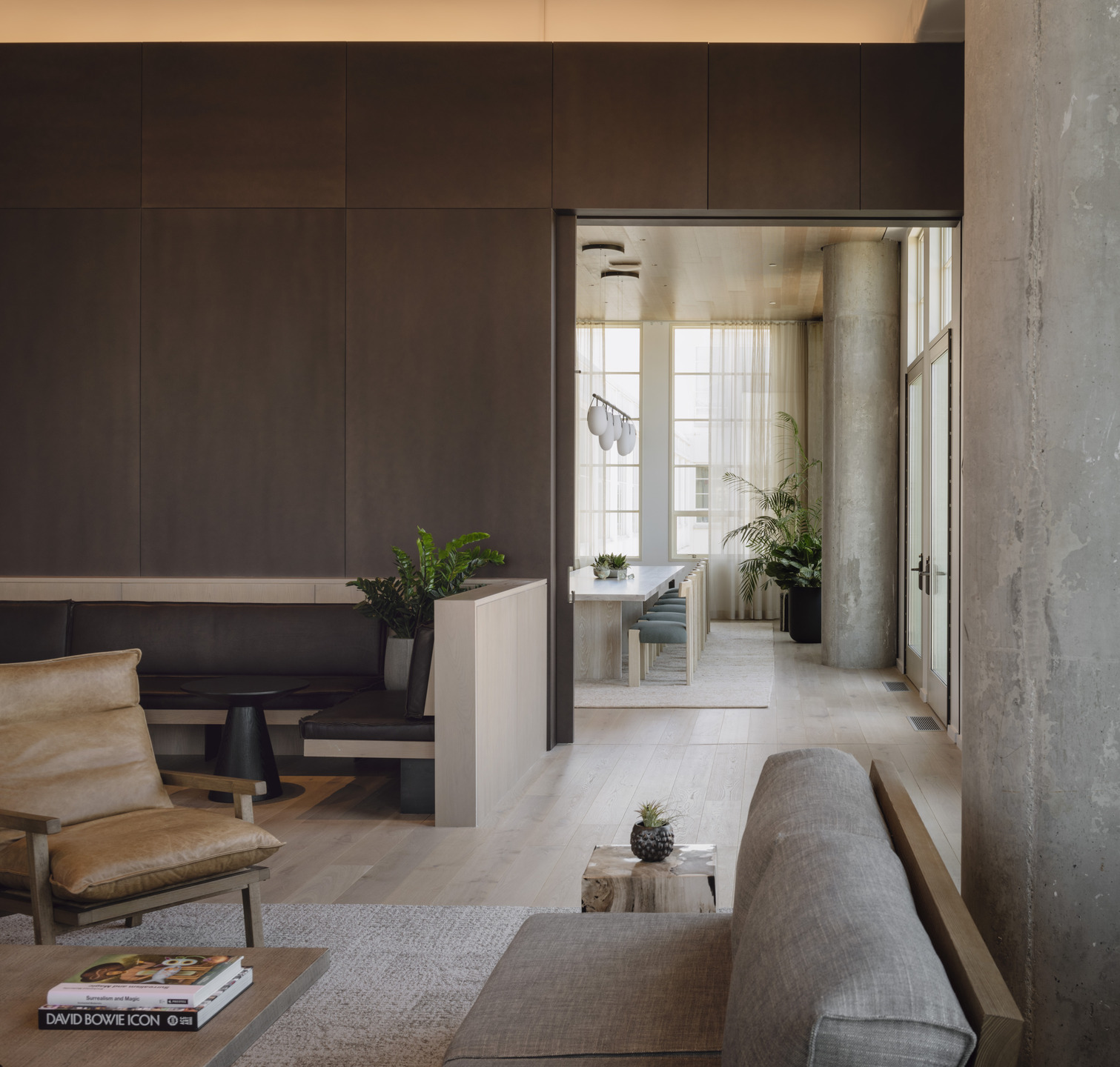 Metal, concrete, and wood accents are softened with potted plants and sunlight from high windows. 