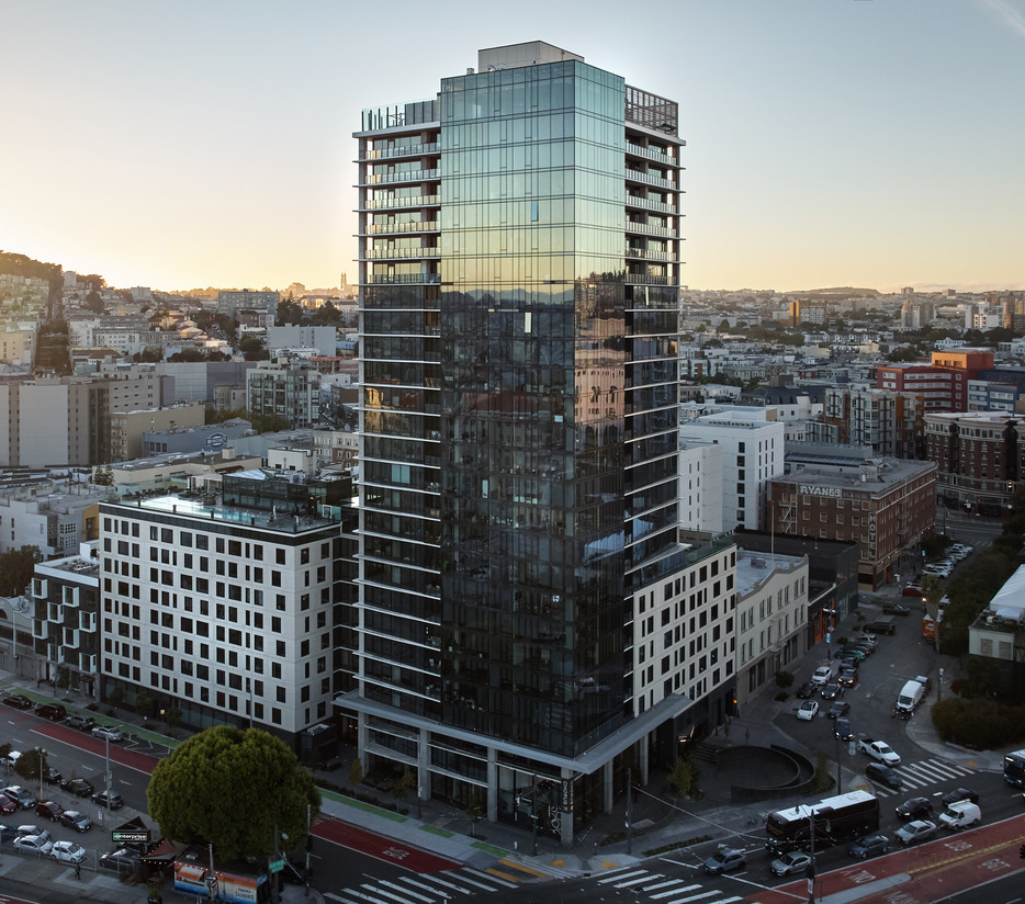 A tall, mixed use building sits within a city.