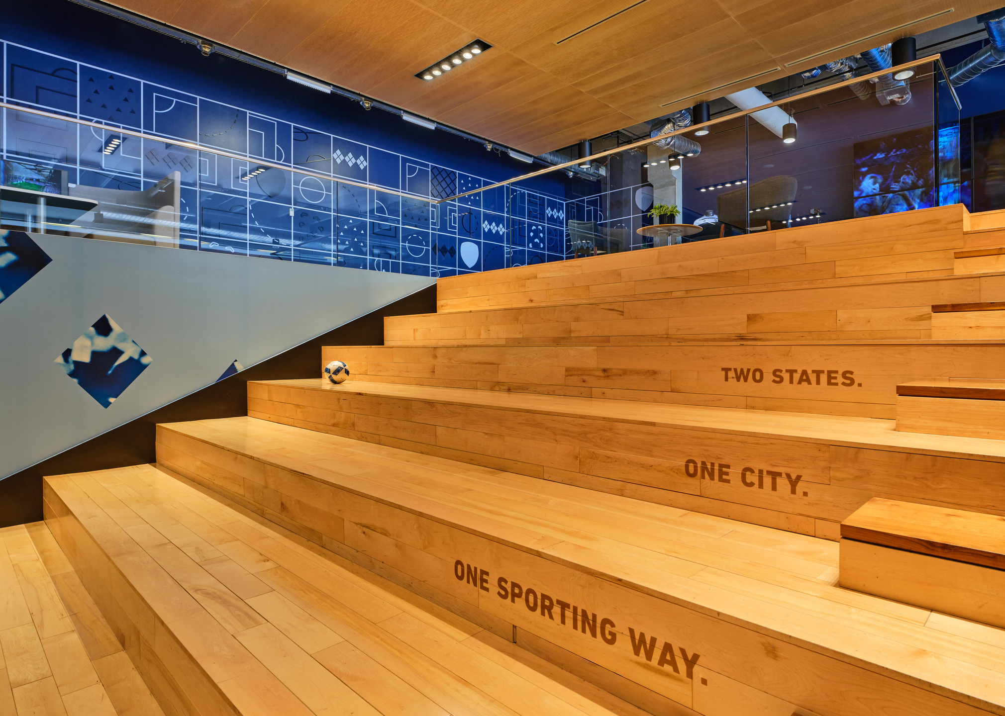A giant light oak staircase connects the upper and lower levels of the workspace.