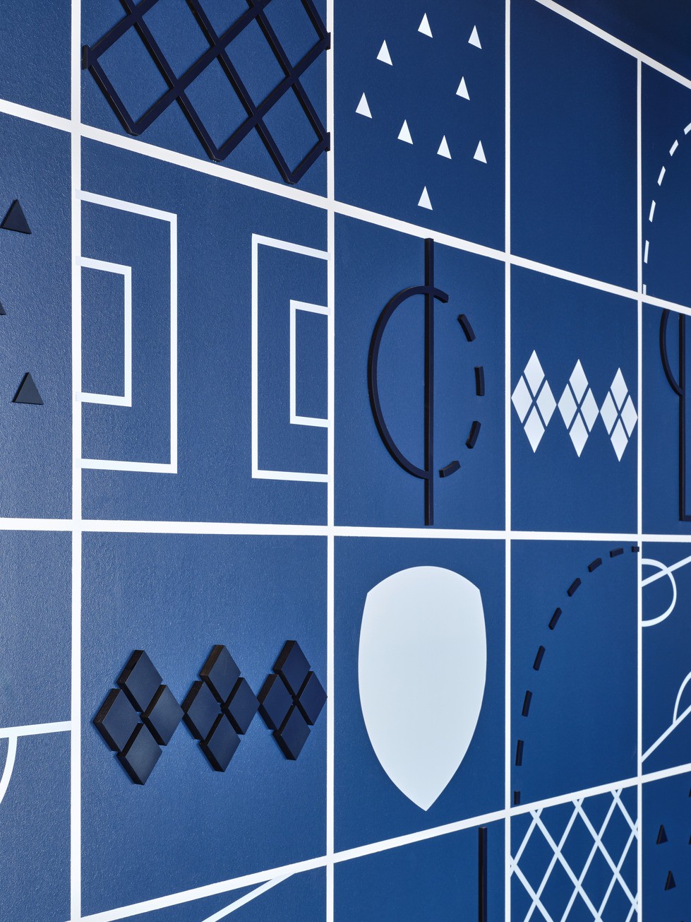 Graphics on the upper walls display different shapes and patterns pulled from a soccer pitch, presented in the Sporting blue brand colors.