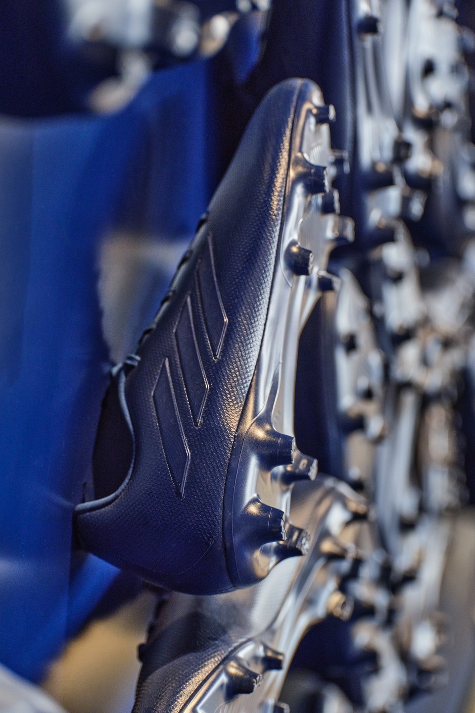 An installation crafted from dark blue Adidas cleats creates a unique textural motif against a dark blue wall.
