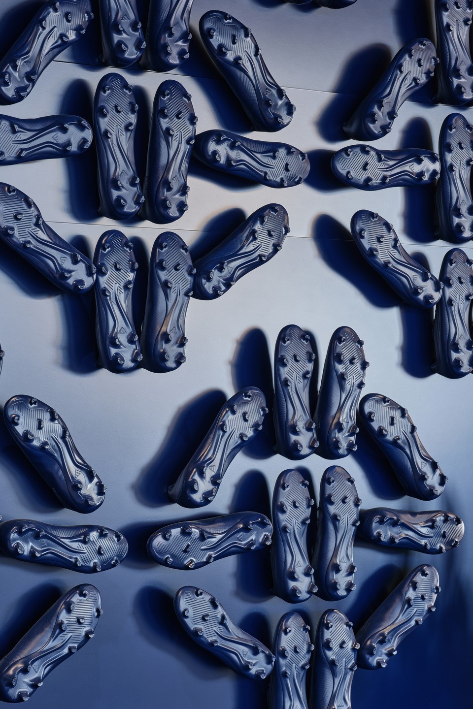An installation crafted from dark blue Adidas cleats creates a unique textural motif against a dark blue wall.