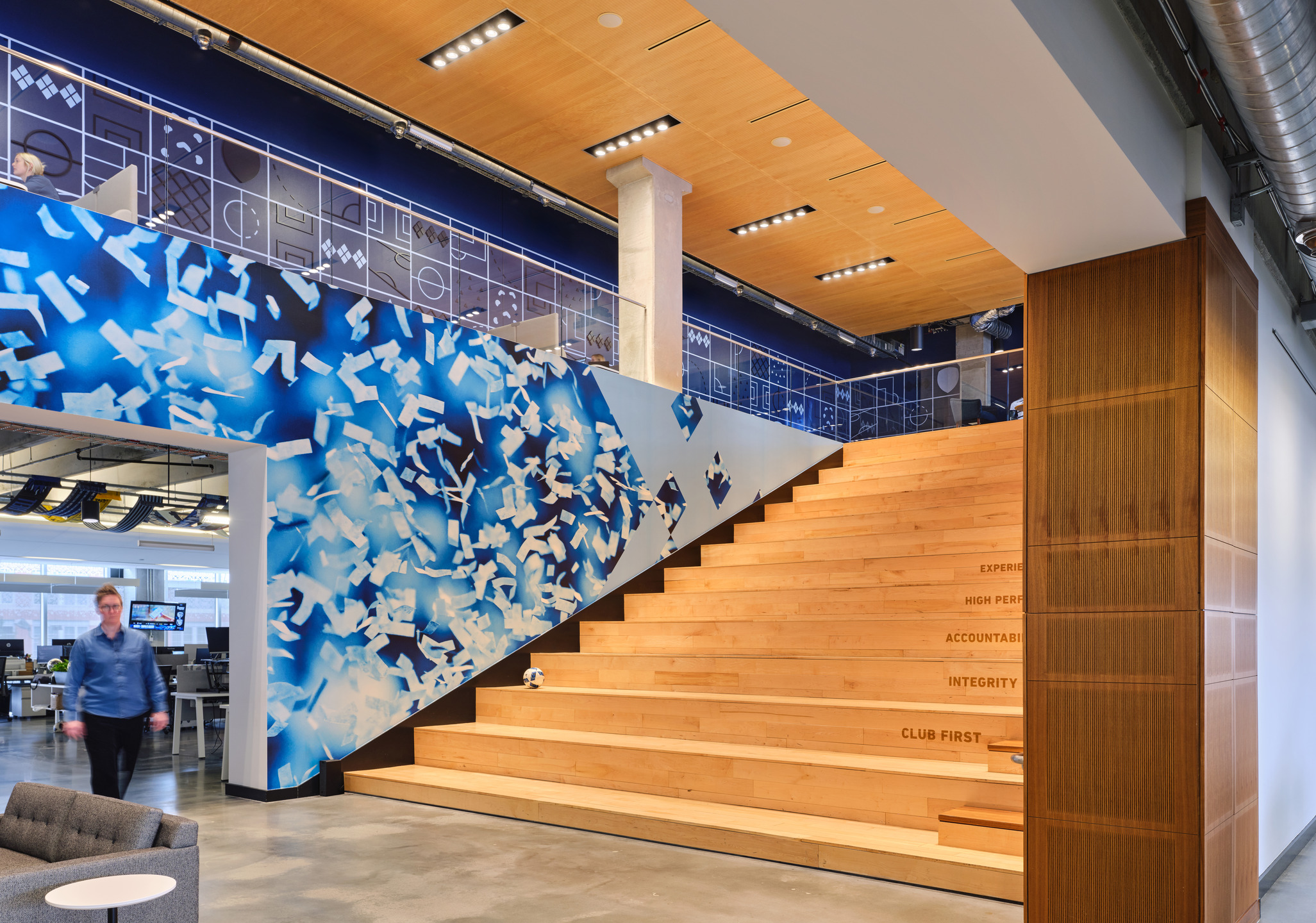 A giant light oak staircase connects the upper and lower levels of the workspace.
