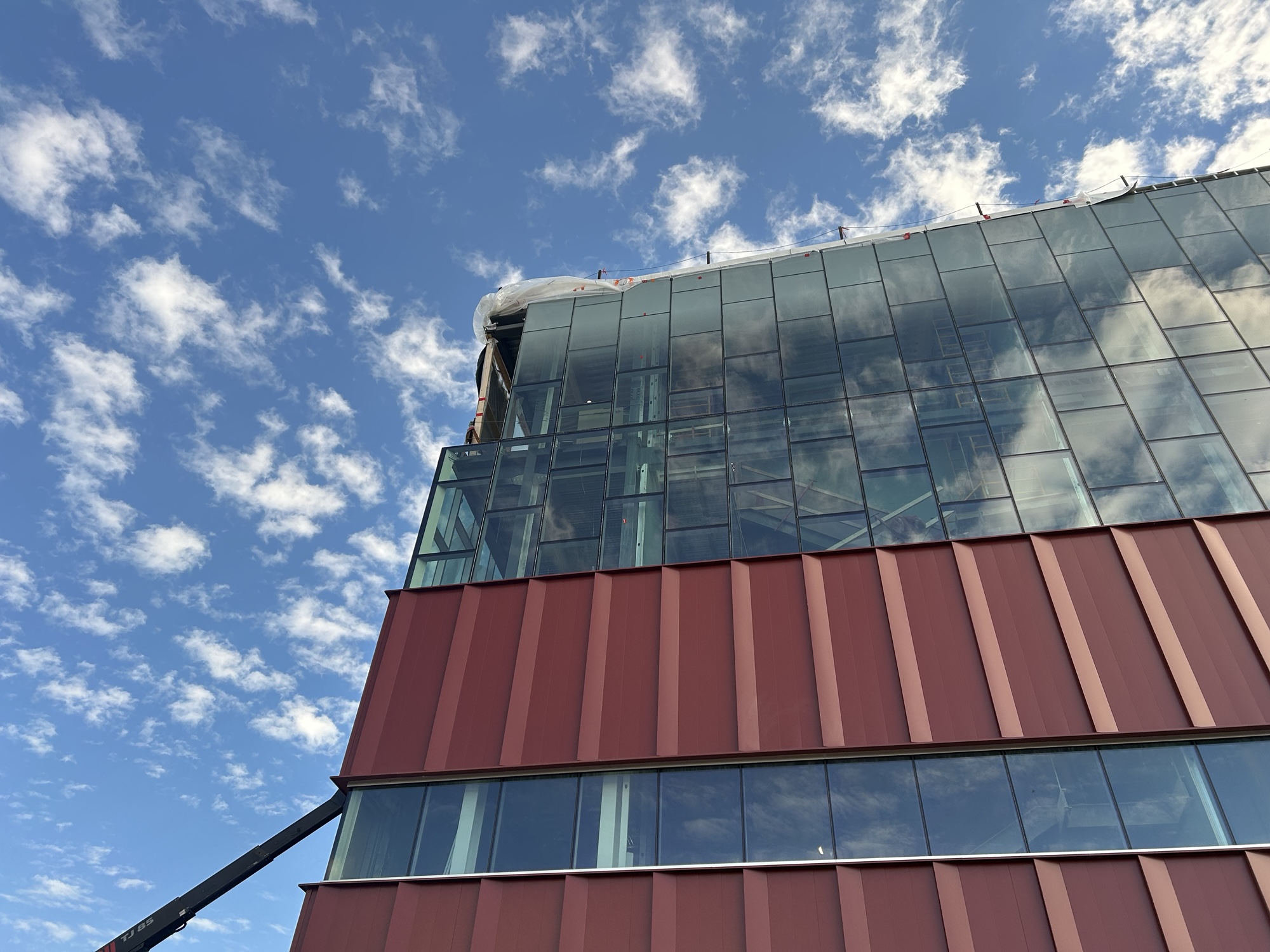 A close up shot shows the progress of glass sheeting being installed on the exterior of the laboratory.