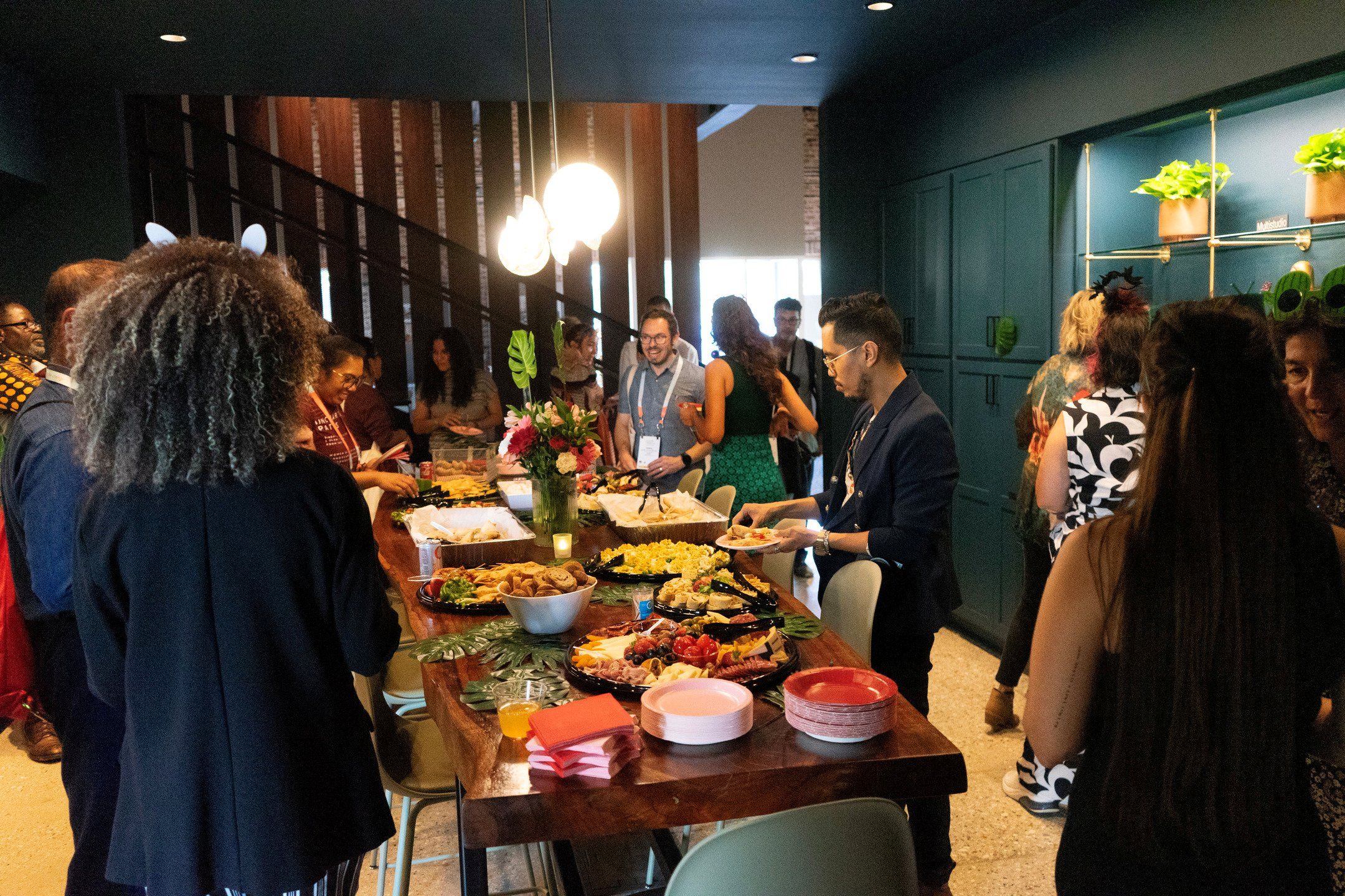 A group of people enjoy a snack spread from a long buffet table.