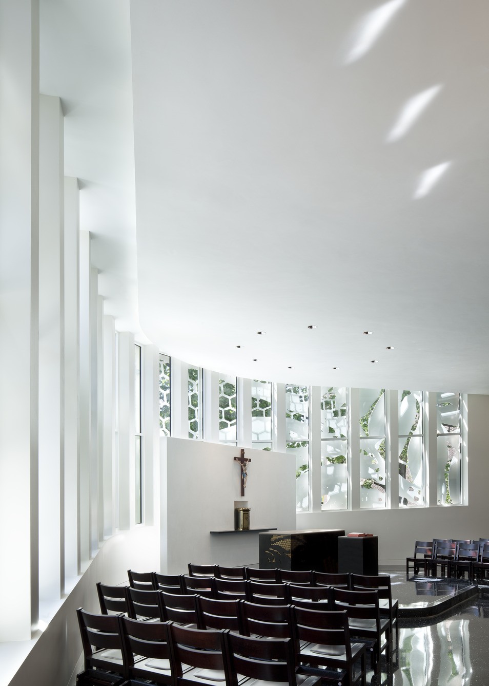 The white, lace-like aluminum scrim is visible through large windows in the chapel.