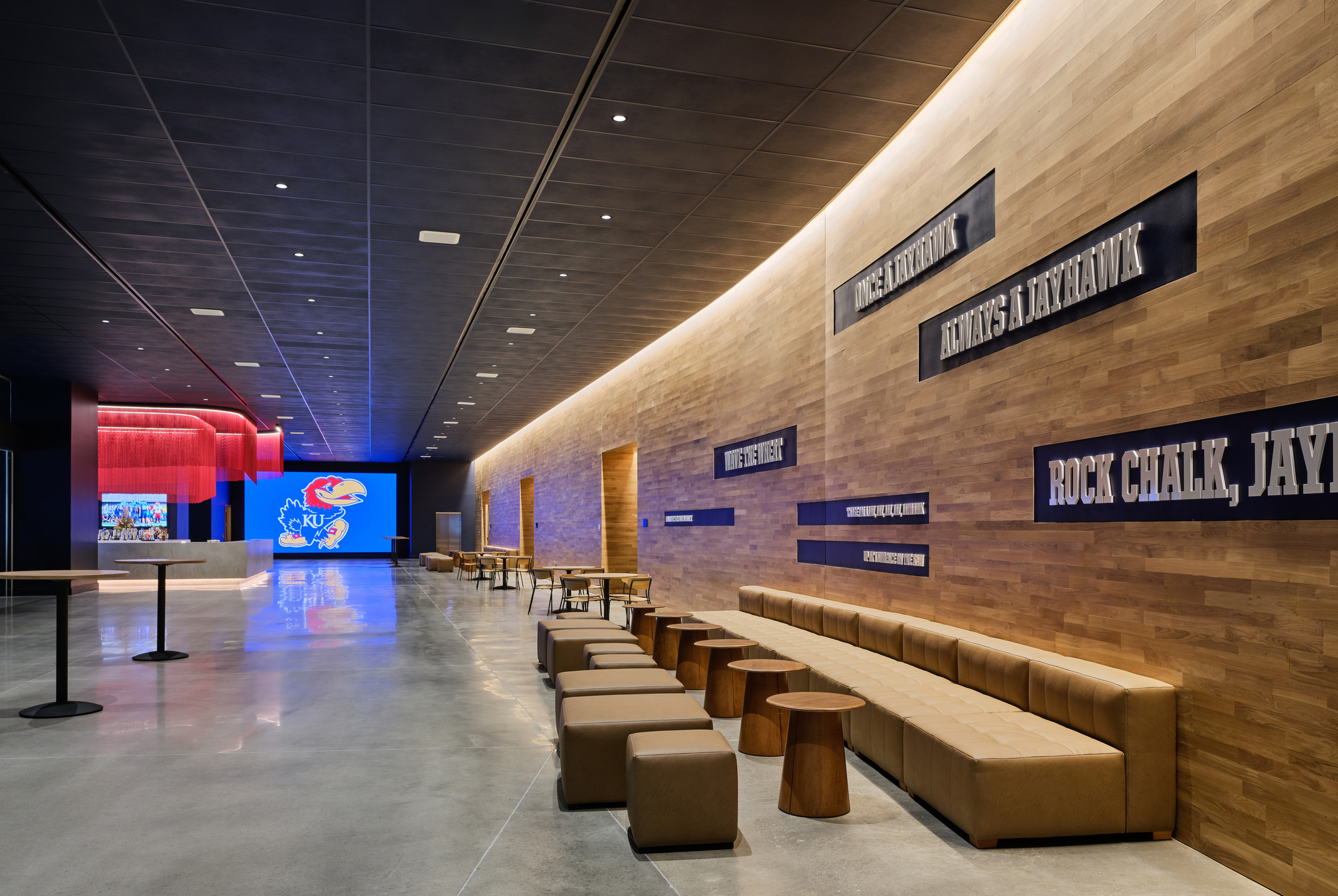 University catch phrases are memorialized on in large white lettering on a wall above long bench seating. 