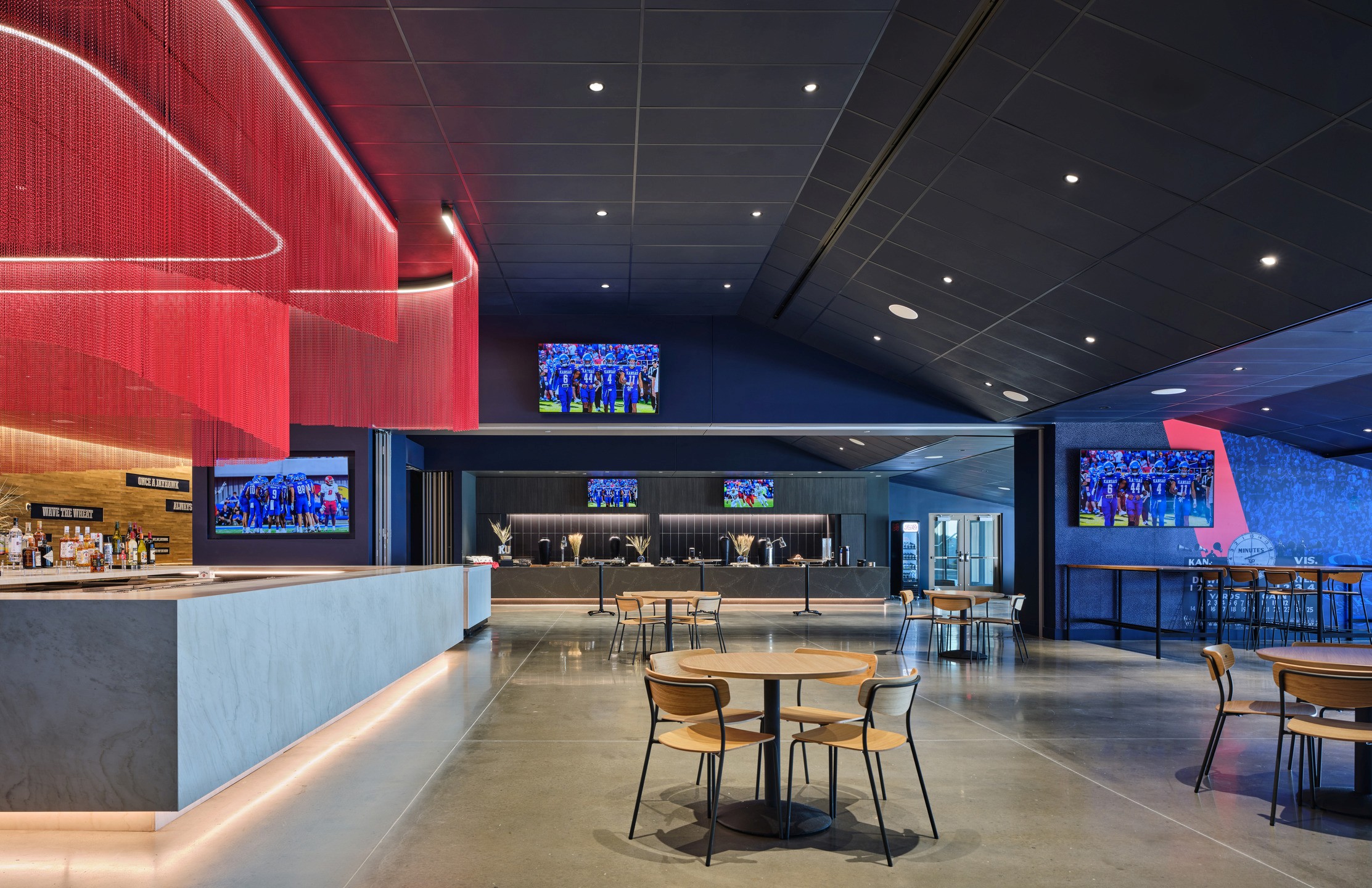 Tables and chairs sit between a 360-degree bar and a buffet table. 