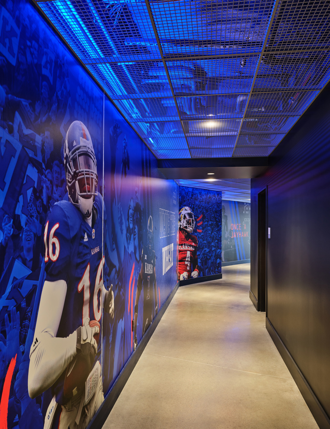 Custom graphics in KU's red and blue brand colors adorn the hall between the Field Club and the stadium.