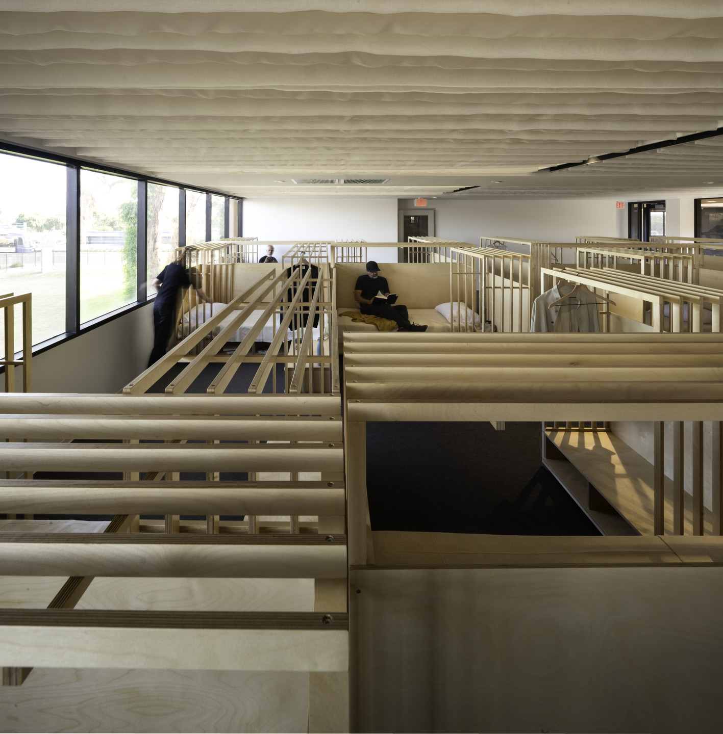 Open-concept bunks crafted from light wood are spread out through a dormitory of matching bed nooks. 