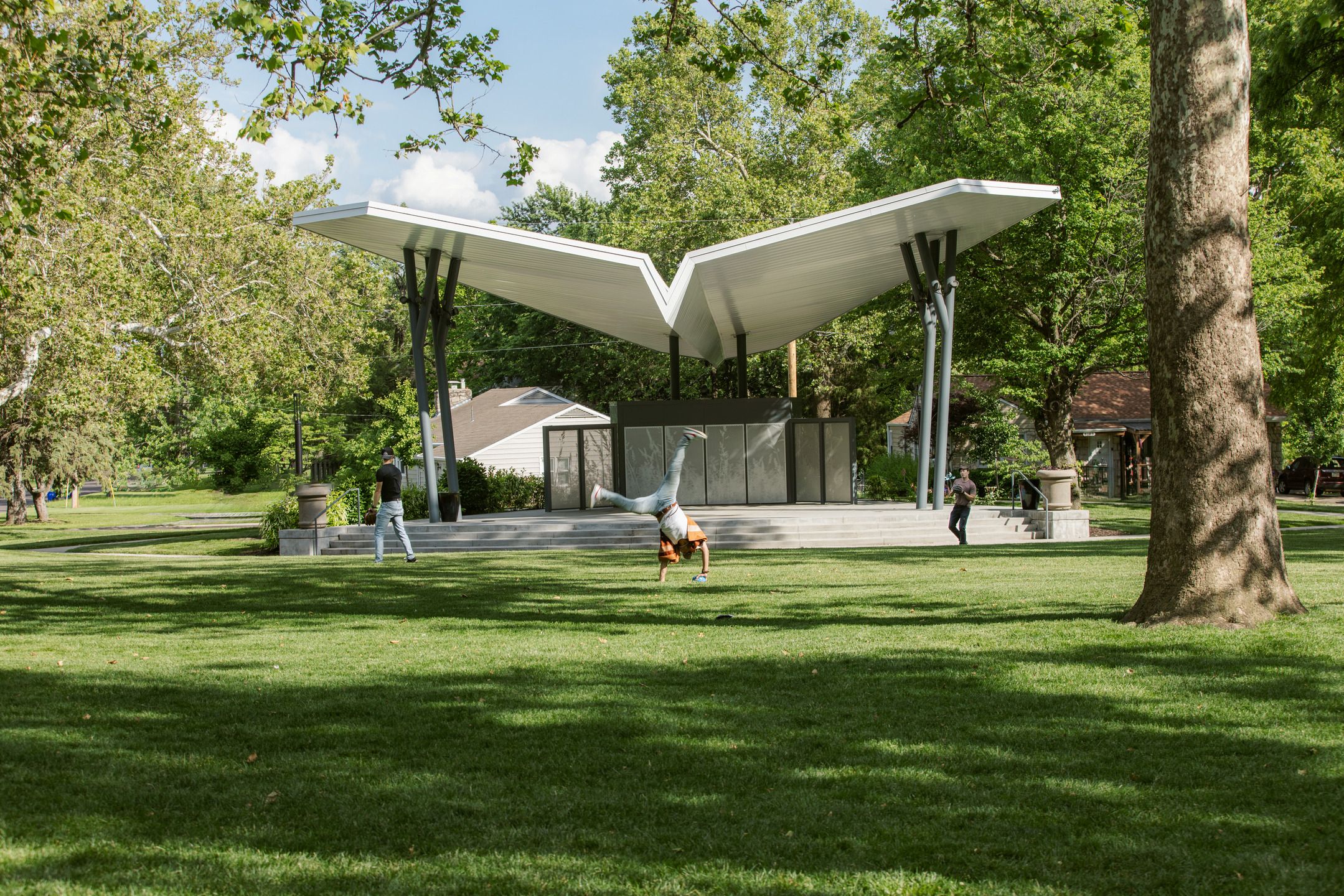 Someone cartwheels in front of a park pavilion.