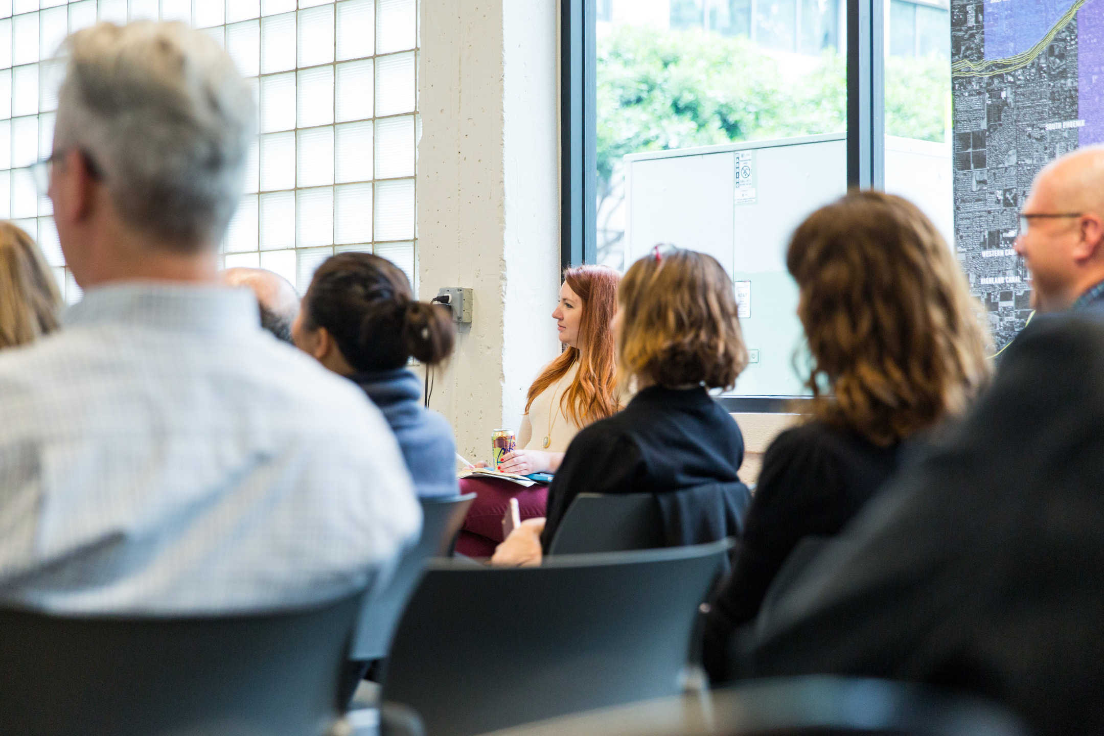 Employees sit in rows of chairs, watching a presentation.