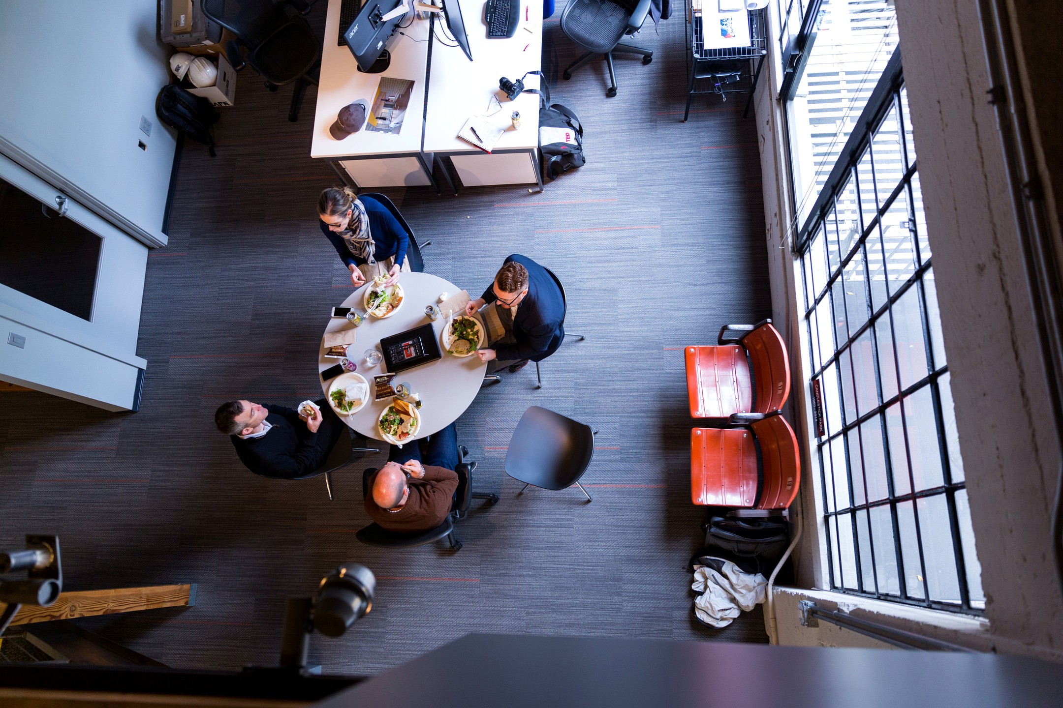 Seen from above, employees eat lunch around a circular table.