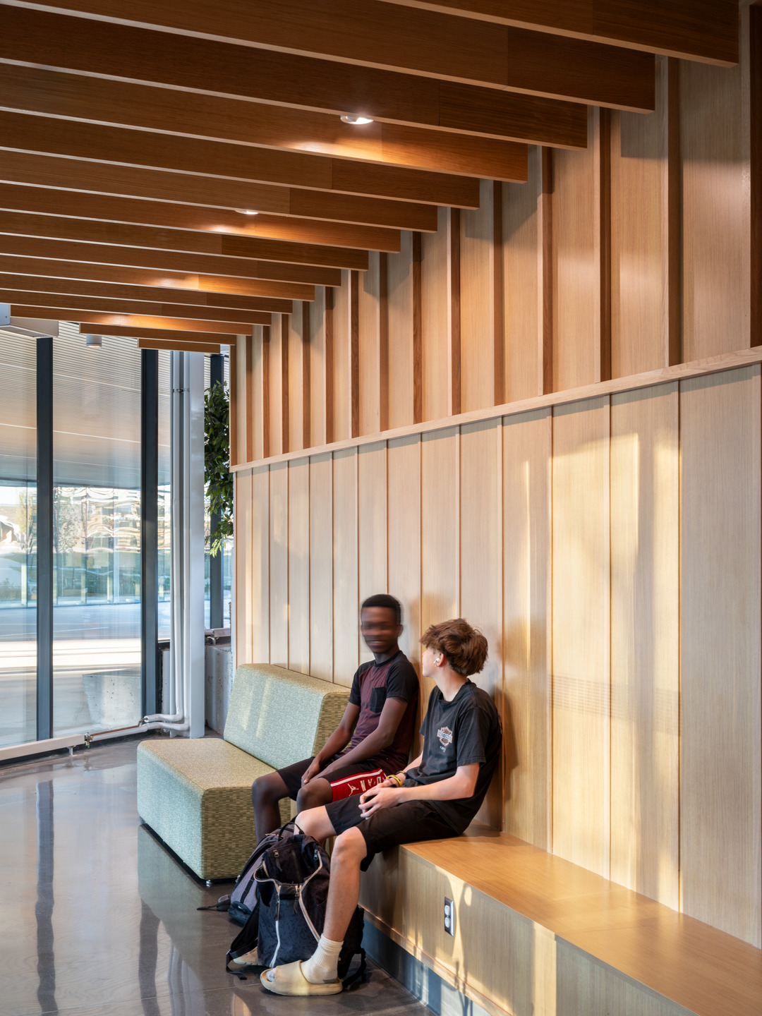 Students sit on a wood bench against wood-paneled walls at Lee's Summit North High School.