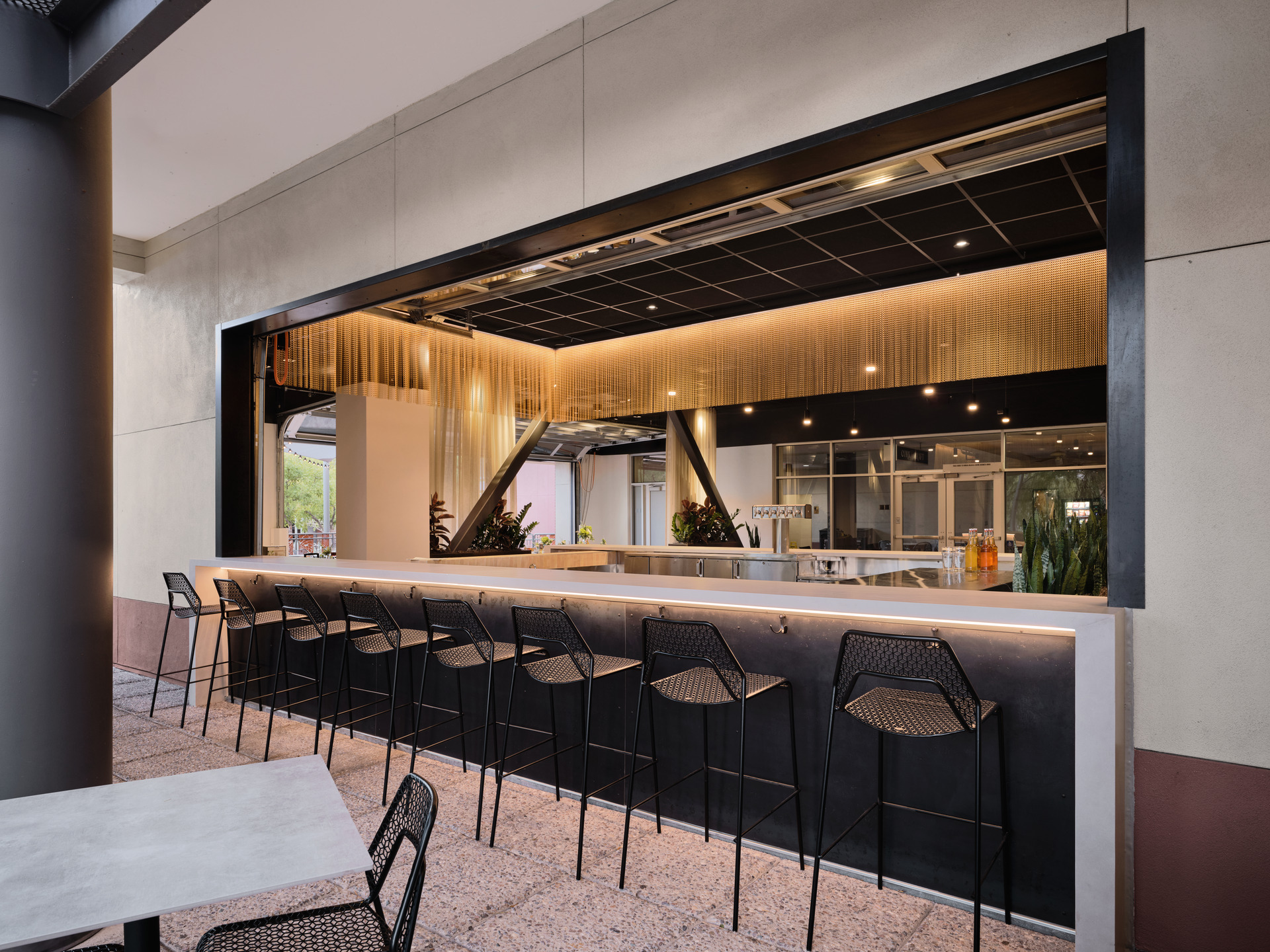 A view into a restaurant with modern decor, bar, and table seating. 