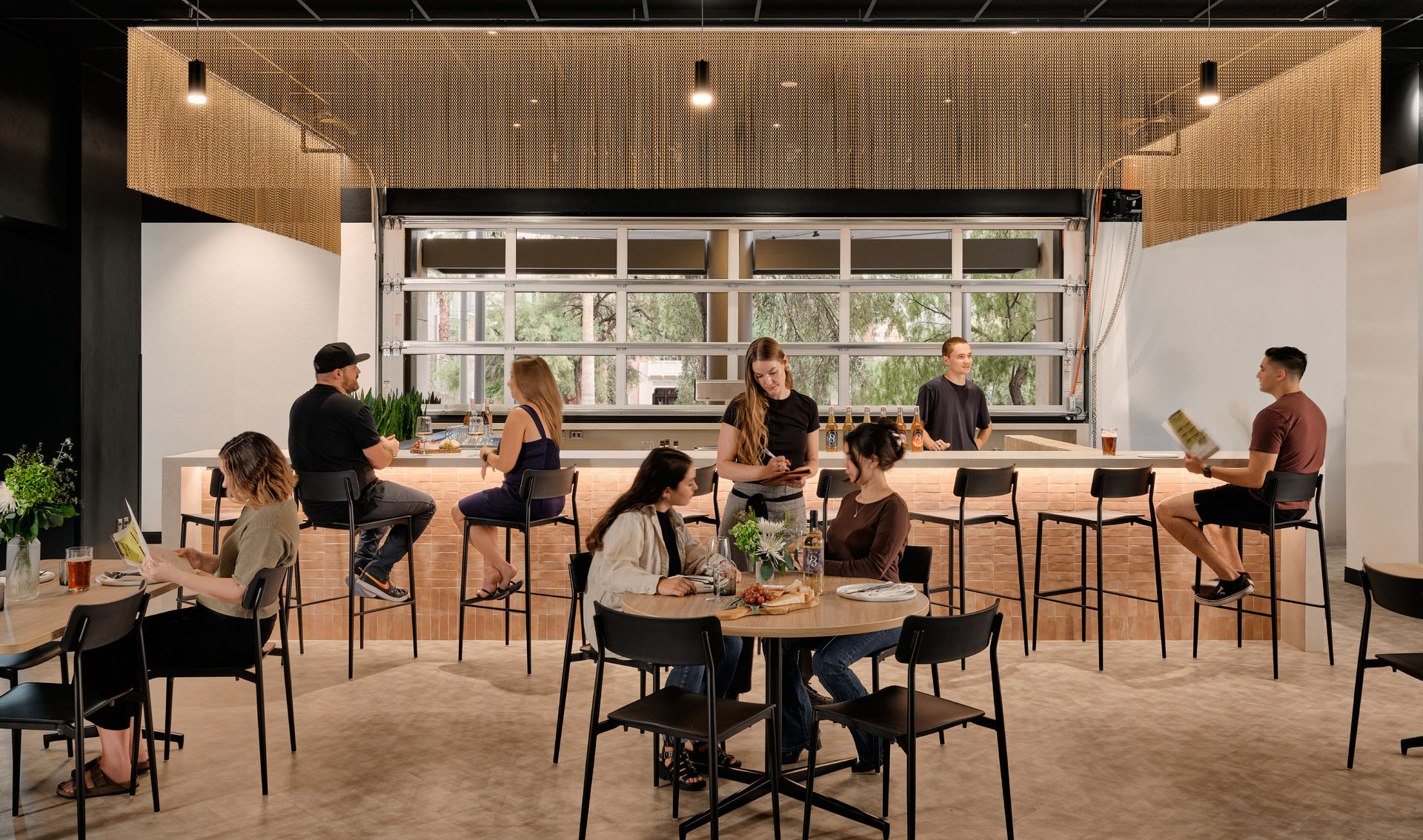 A view into a restaurant with modern decor, bar, and table seating.