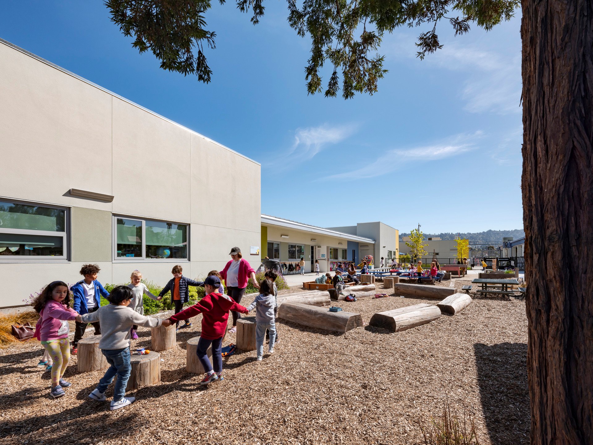 Students holding hands in a circle and playing in a school play yard.