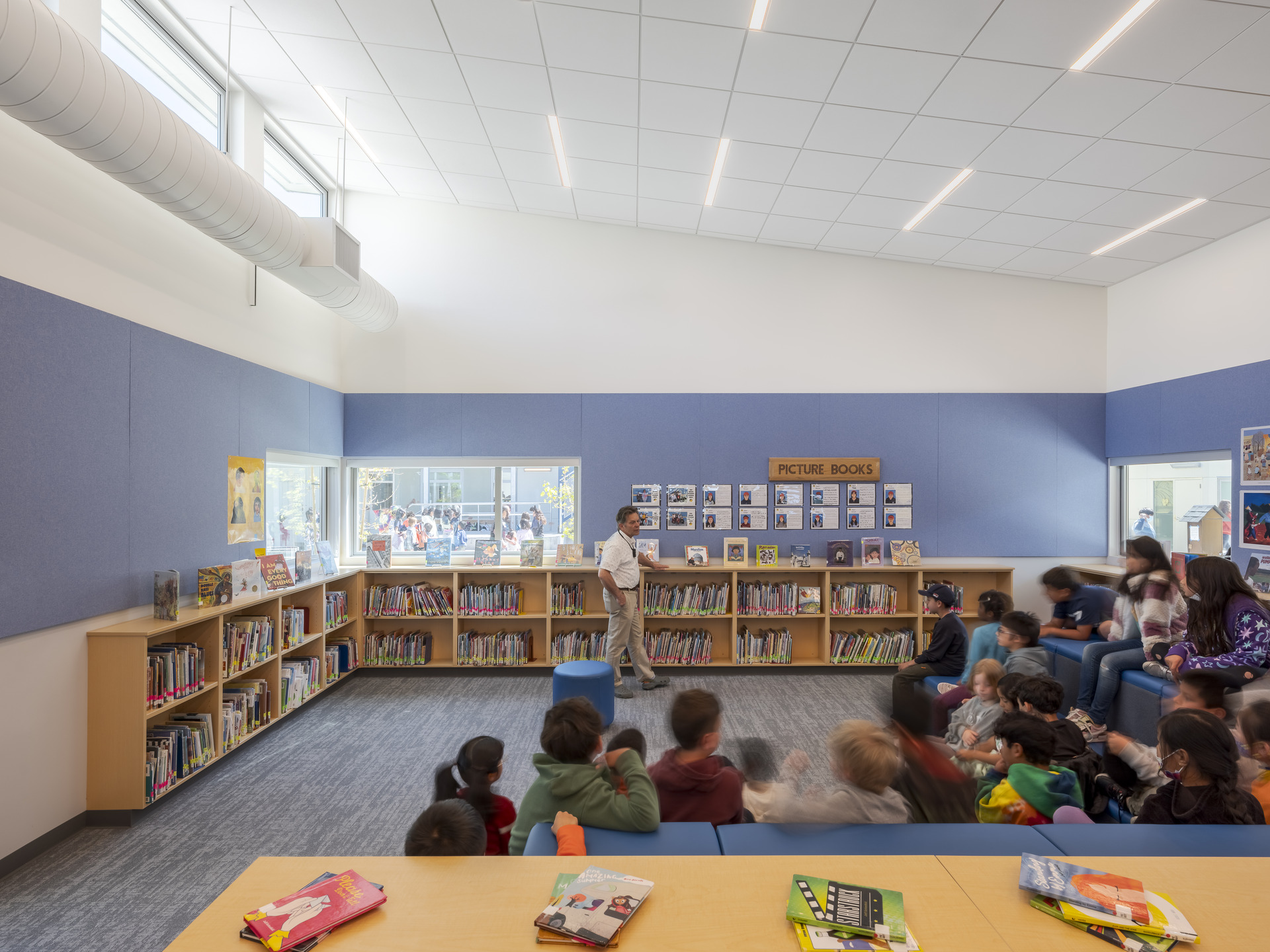 Students gathered around a librarian in a library for story time.