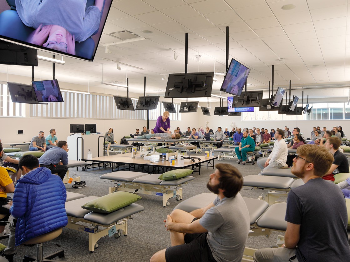 Chiropractic students at KCU sit in a class, watching a demo. 