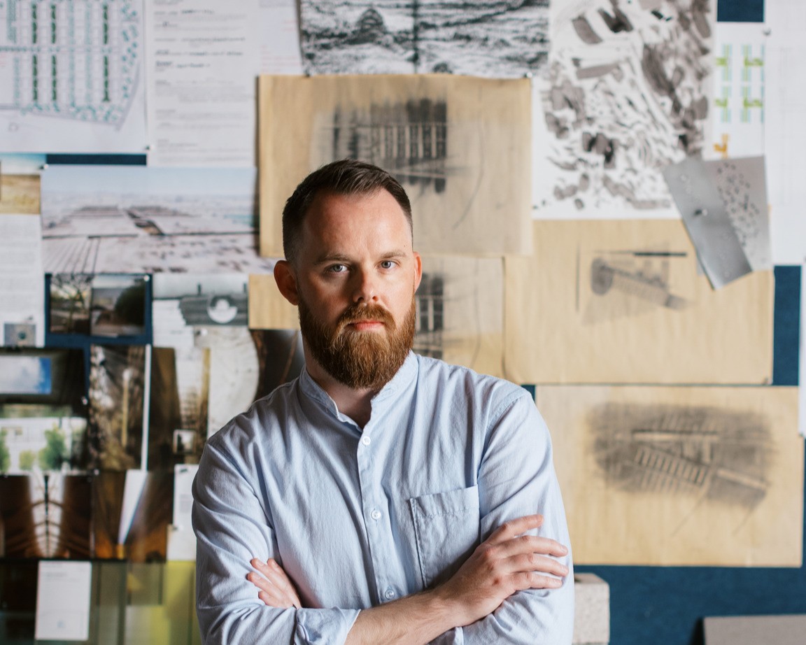 Joey Gamblin stands in front of a project wall.