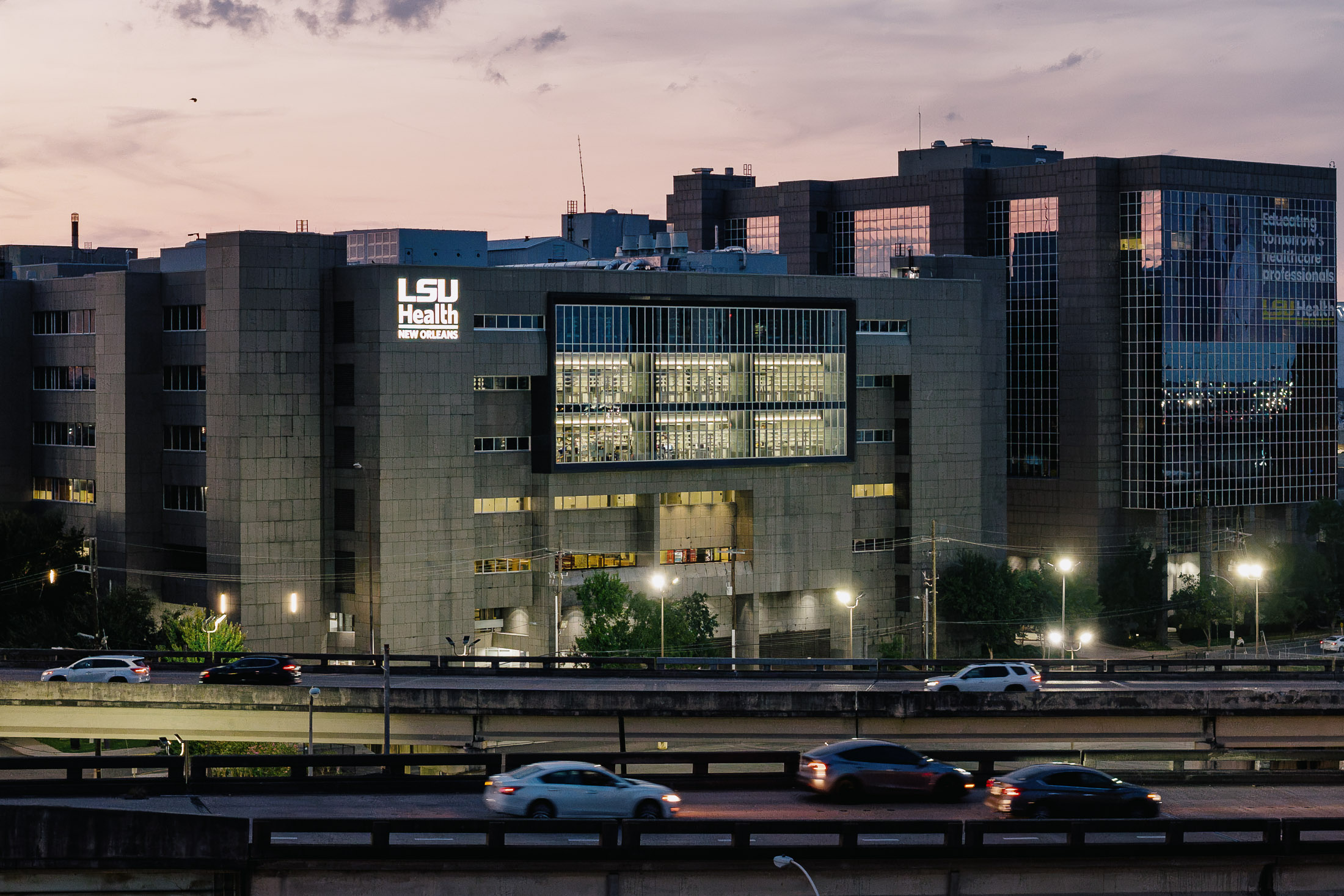 An aerial shot of the renovated LSU research lab at dusk with an elevated roadway in the foreground.