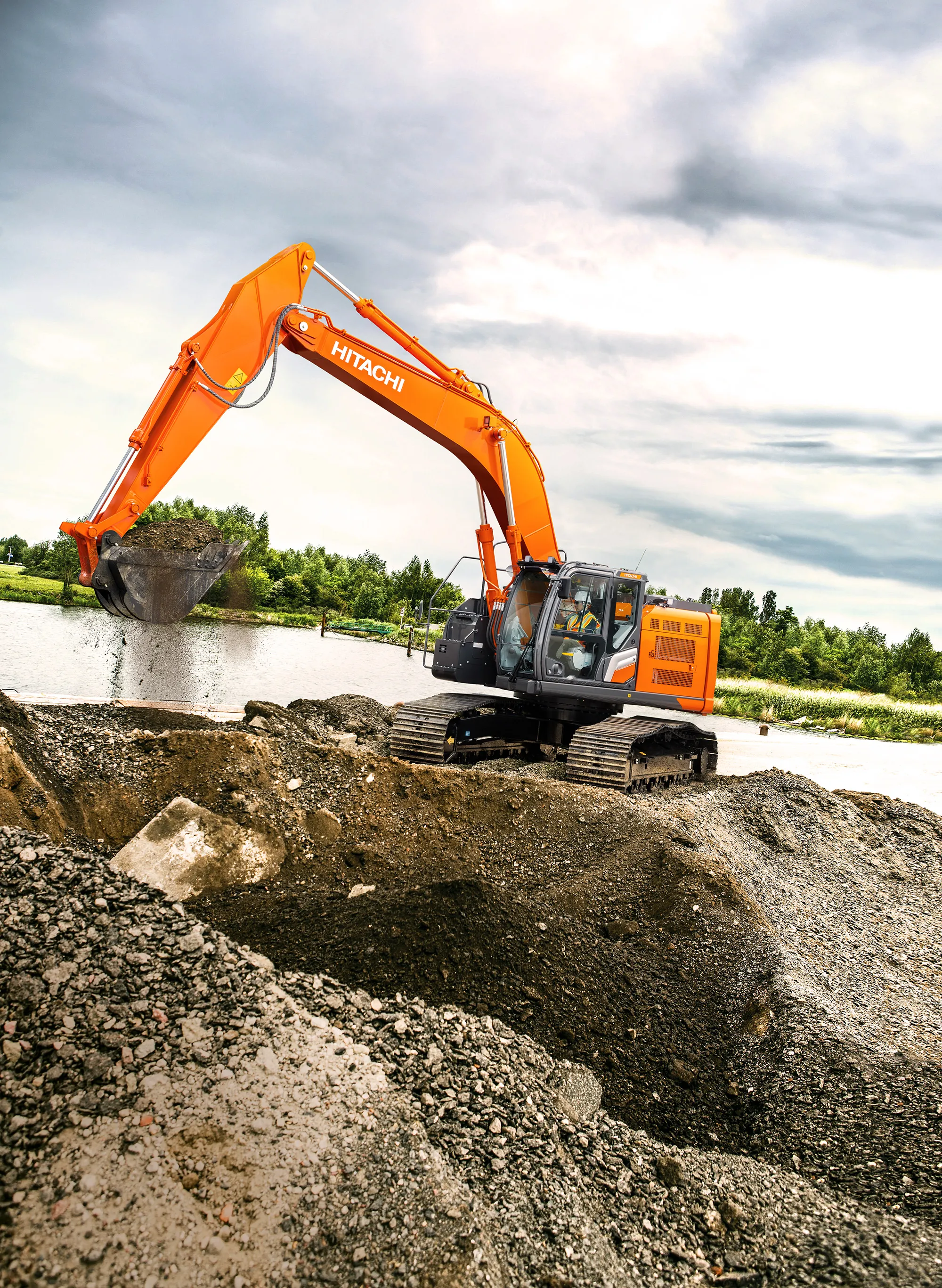 A Hitachi excavator moving gravel and dirt at an active job site.