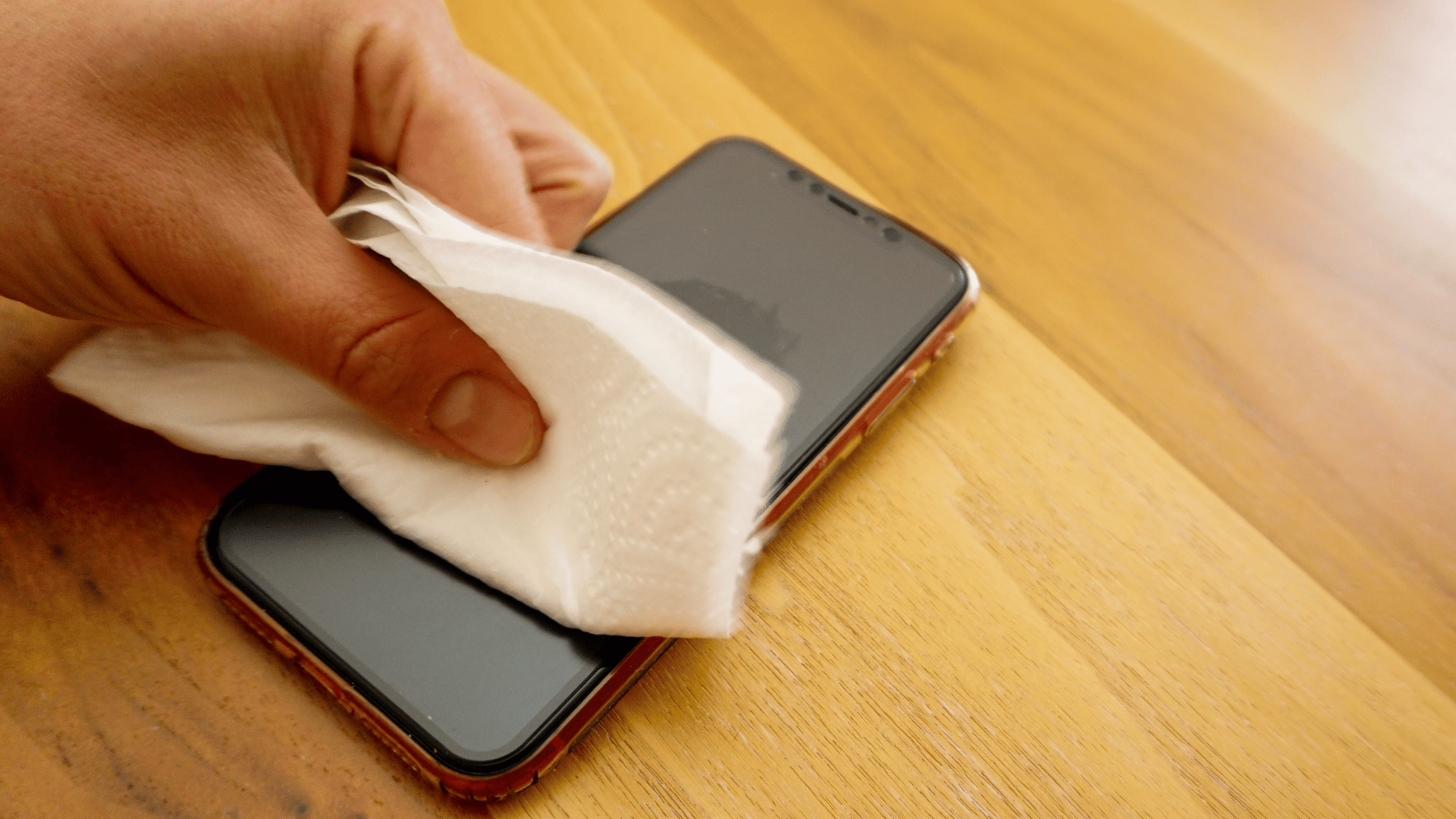 a person drying a mobile withpaper towel
