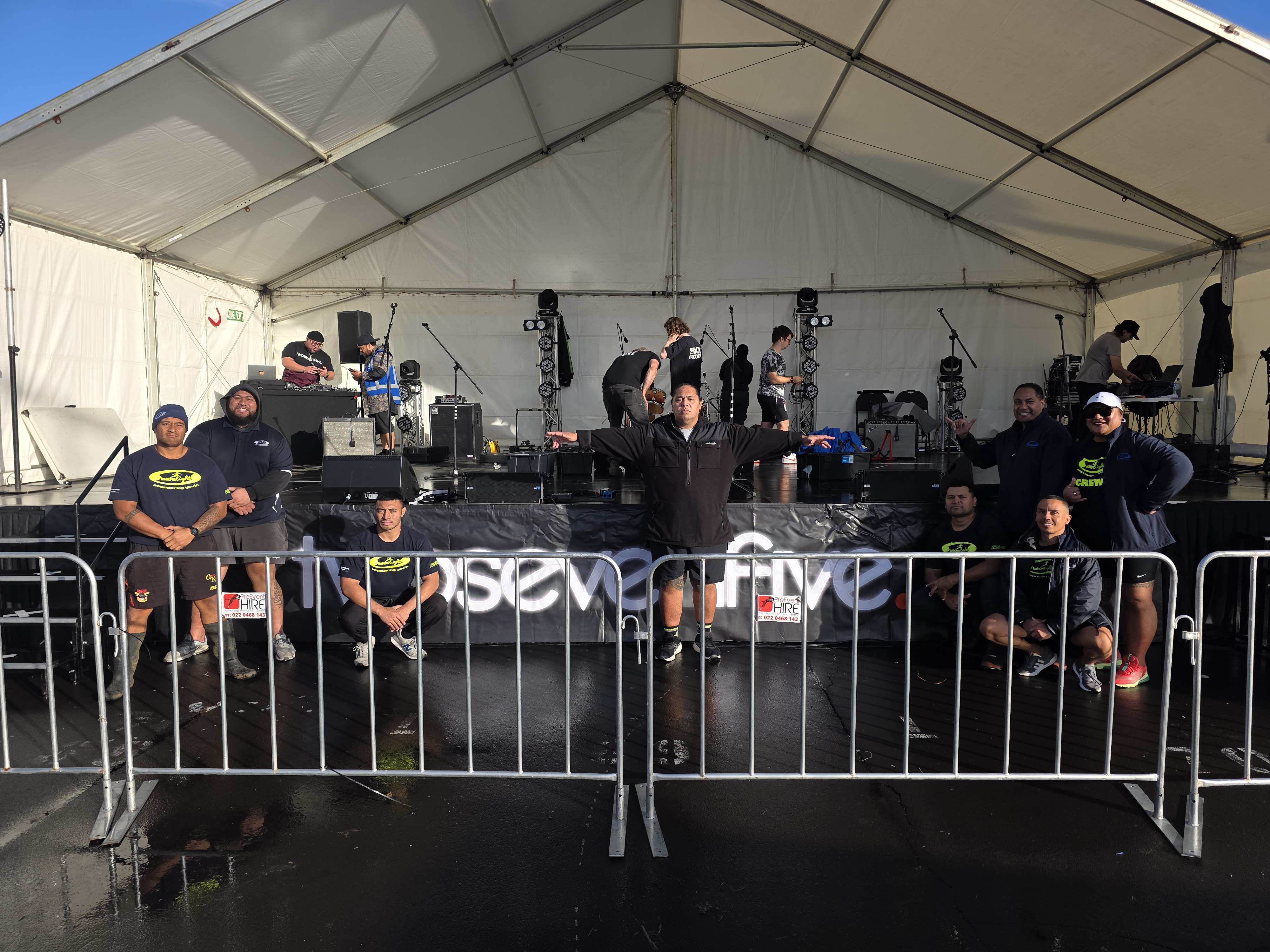 Three people on stage singing with colourful lights and smoke surrounding them
