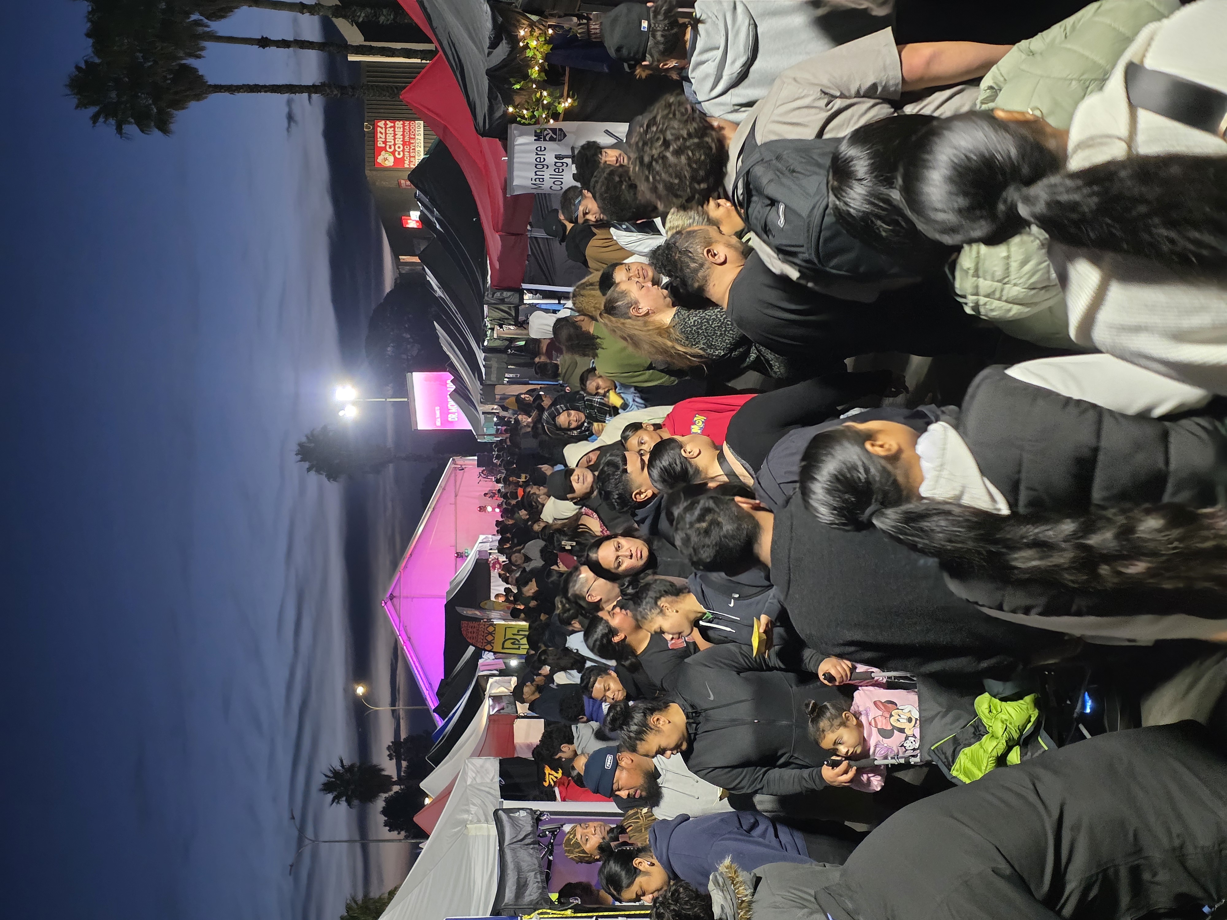 A girl weaing a pink rain jacket sitting on her parents shoulders