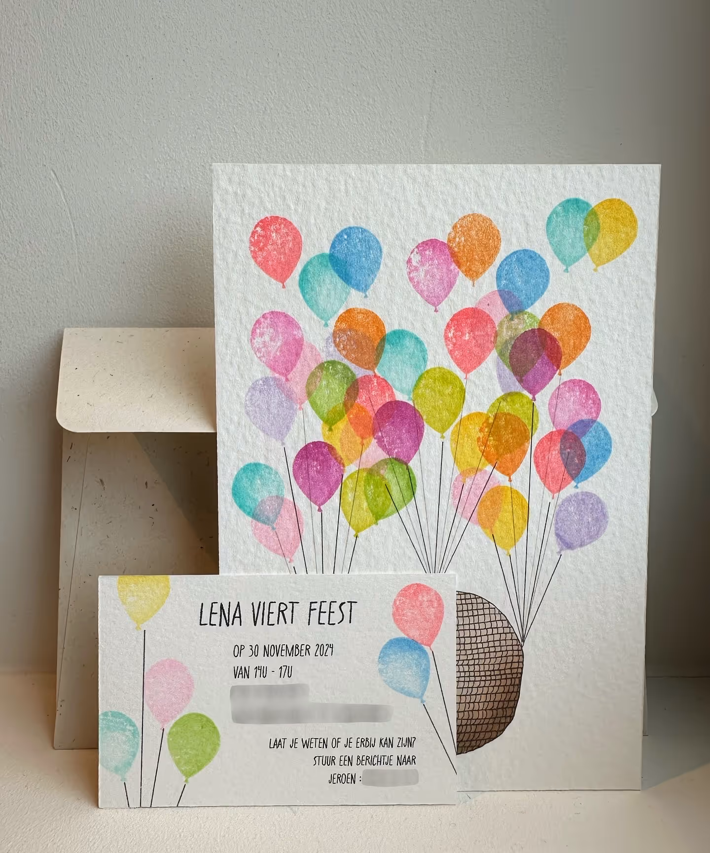 Foto van het geboortekaartje en de uitnodiging met handgestempelde ballonnen van de babyborrel van Baby Lena
