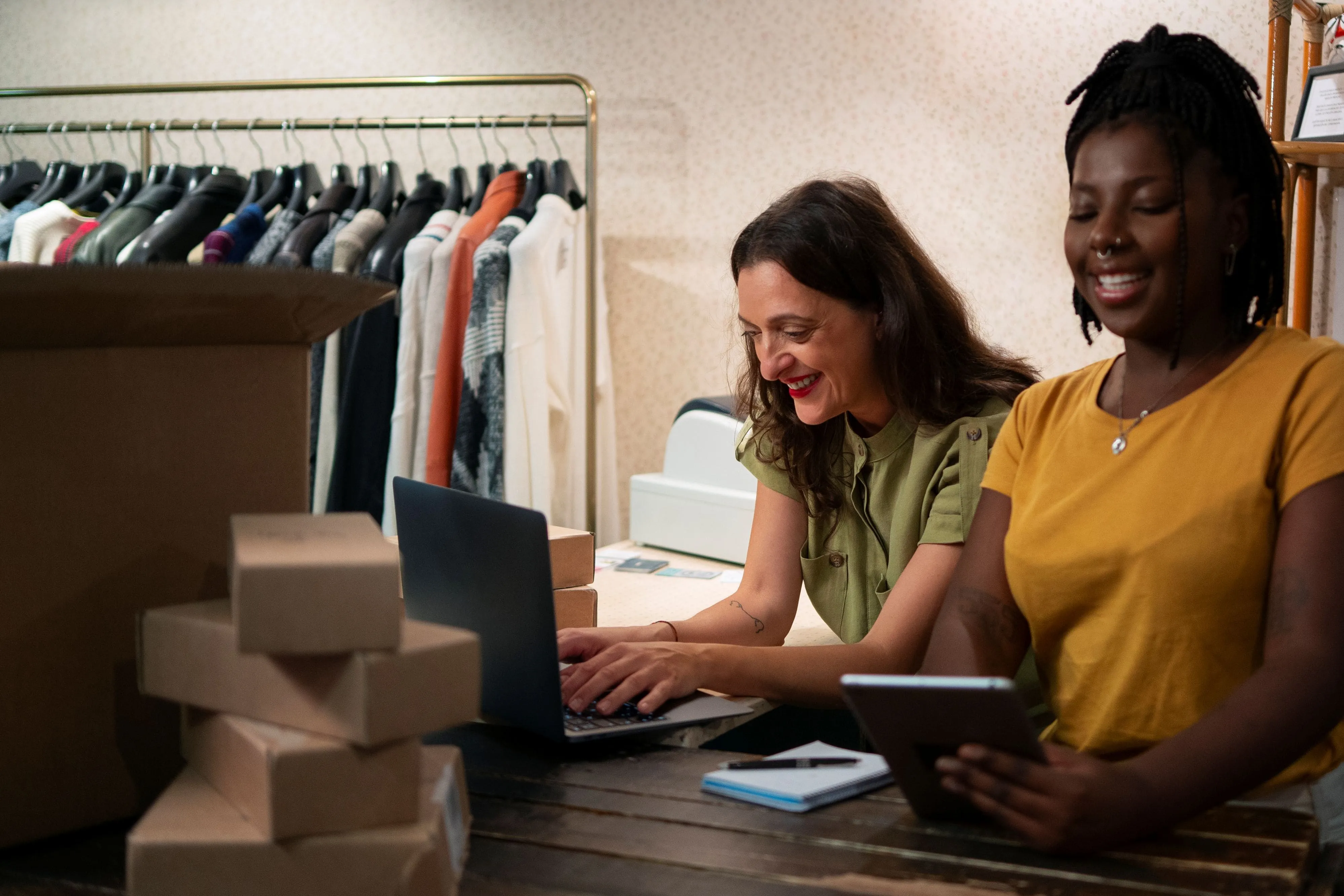 Two smiling female entrepreneurs in their workshop, managing their Woocommerce sales tax