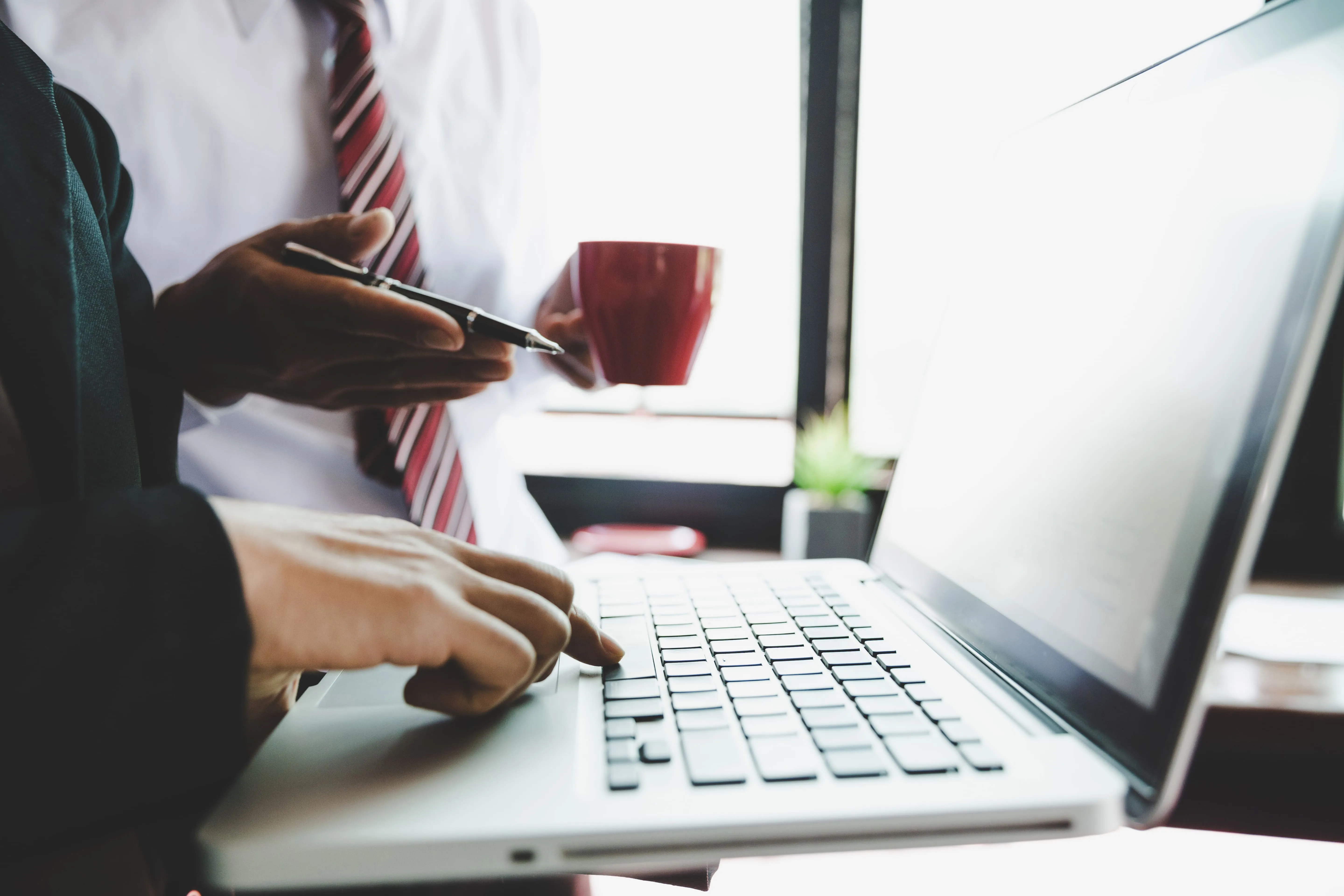 The hands of two business people discussing global VAT registration over a laptop