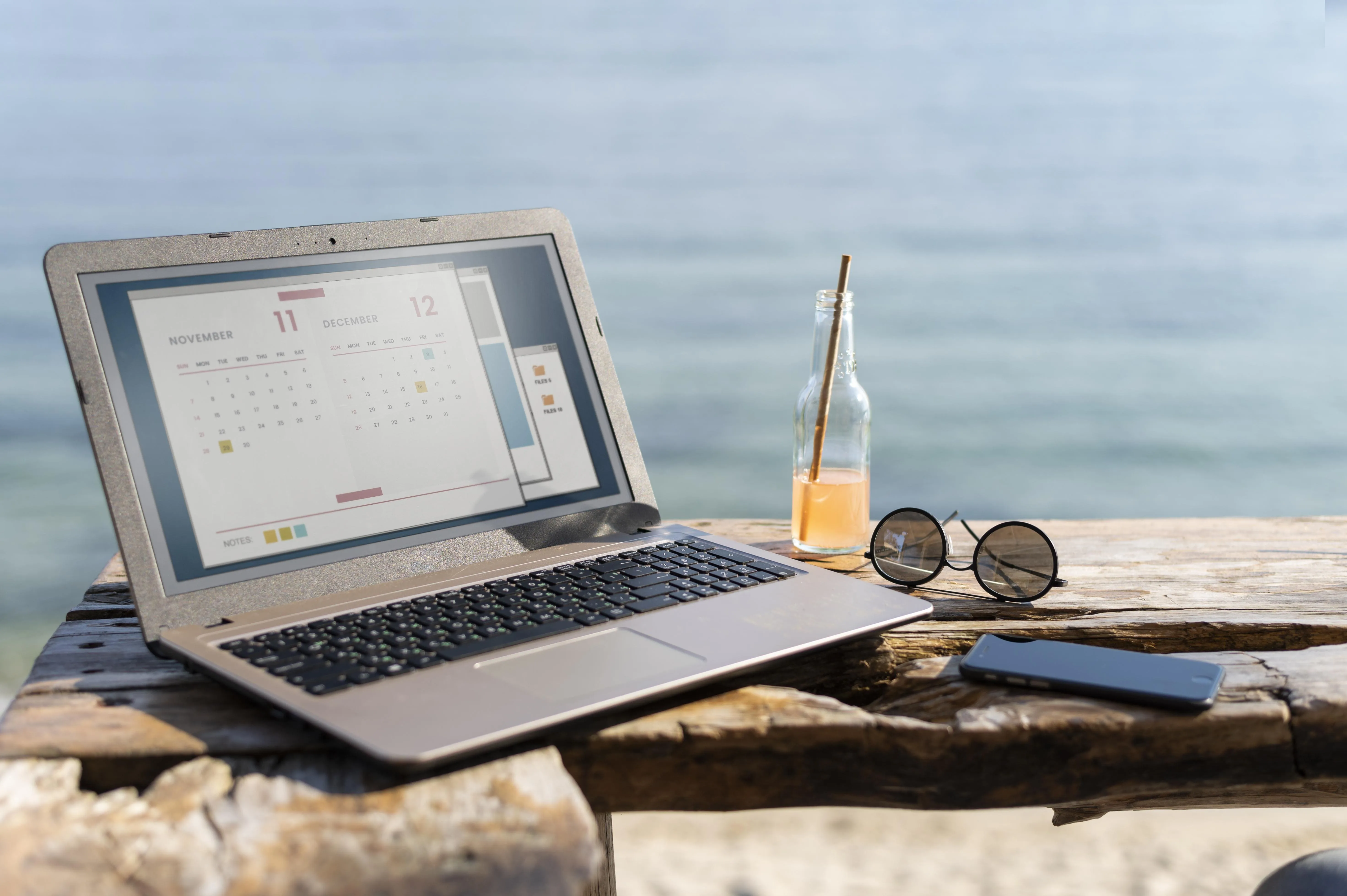 A laptop displaying an open calendar with a drink and sunglasses showing sales tax holidays