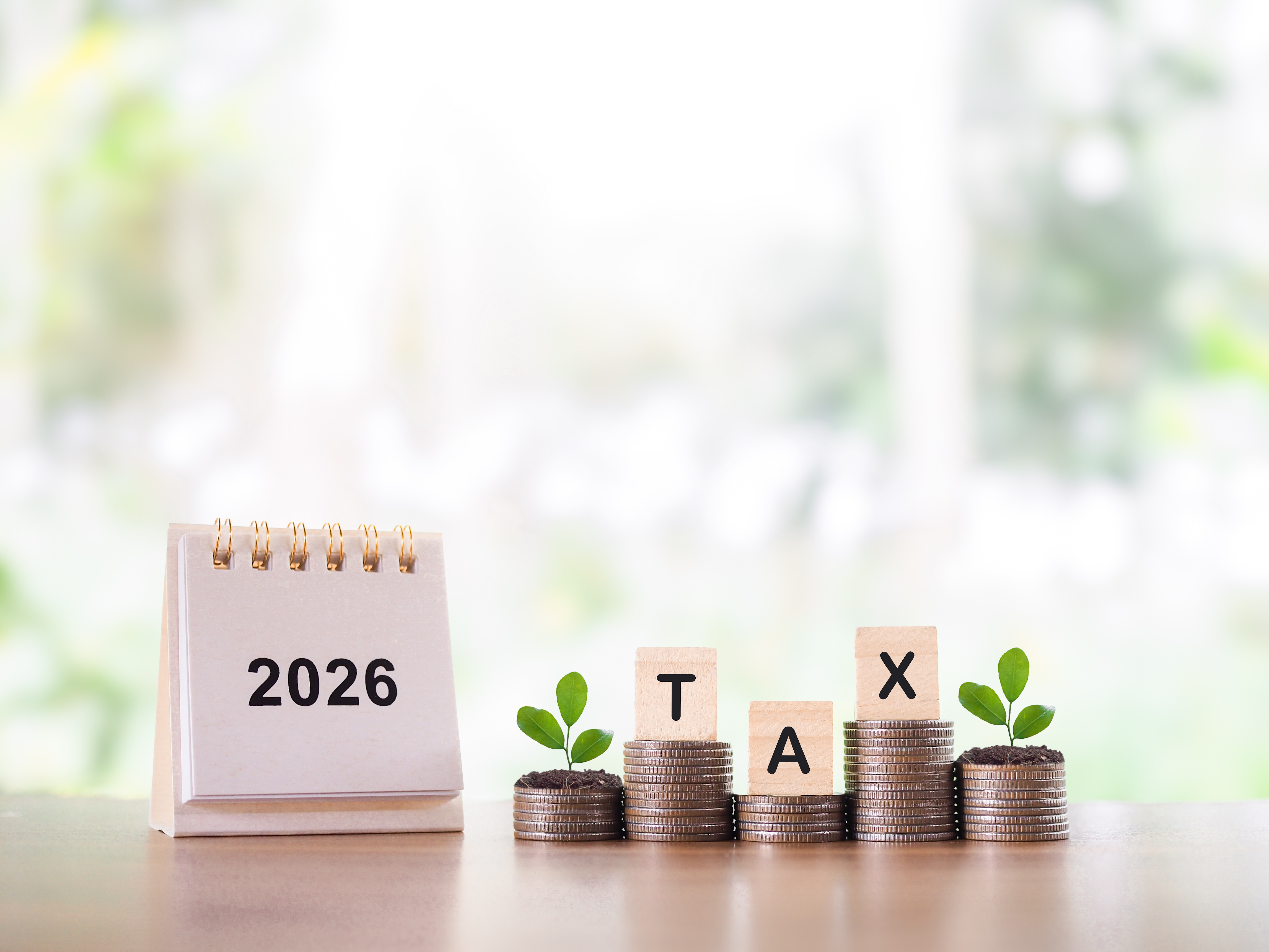 A business owner tracking sales tax trends in 2026 with a calendar and stacked coins.