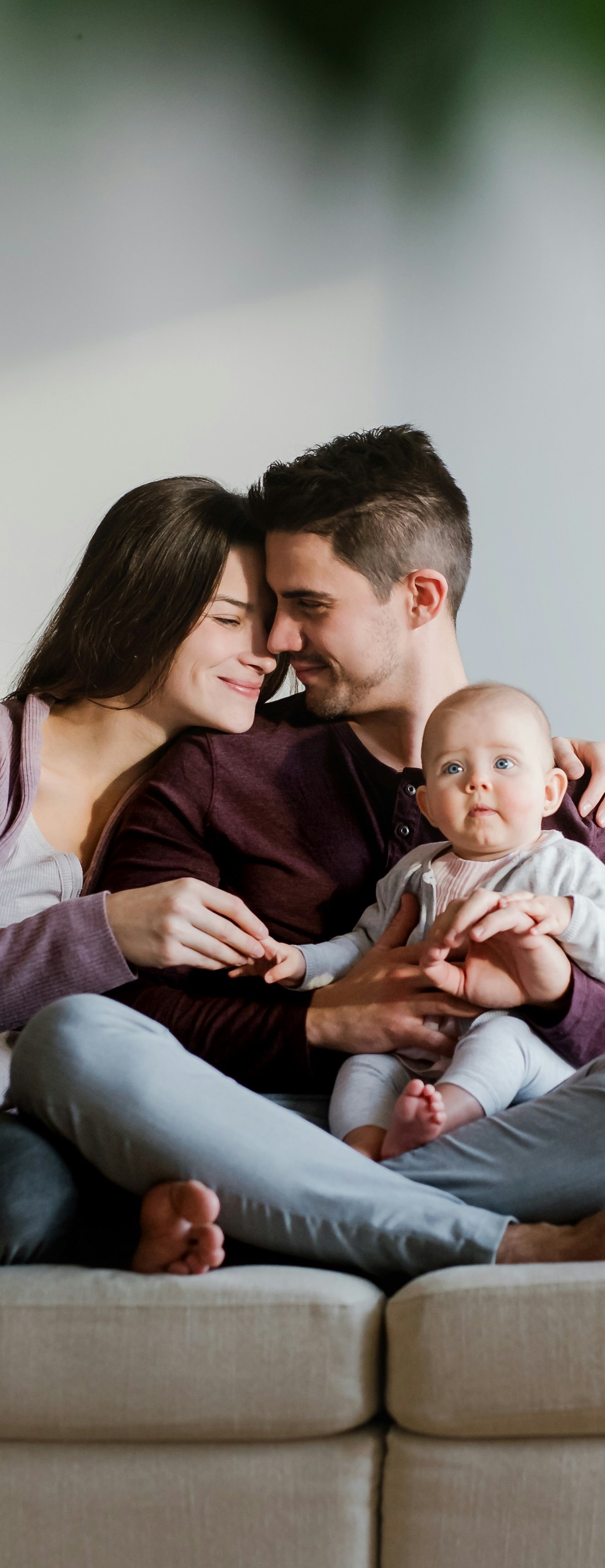 parents holding their baby sitting on the couch