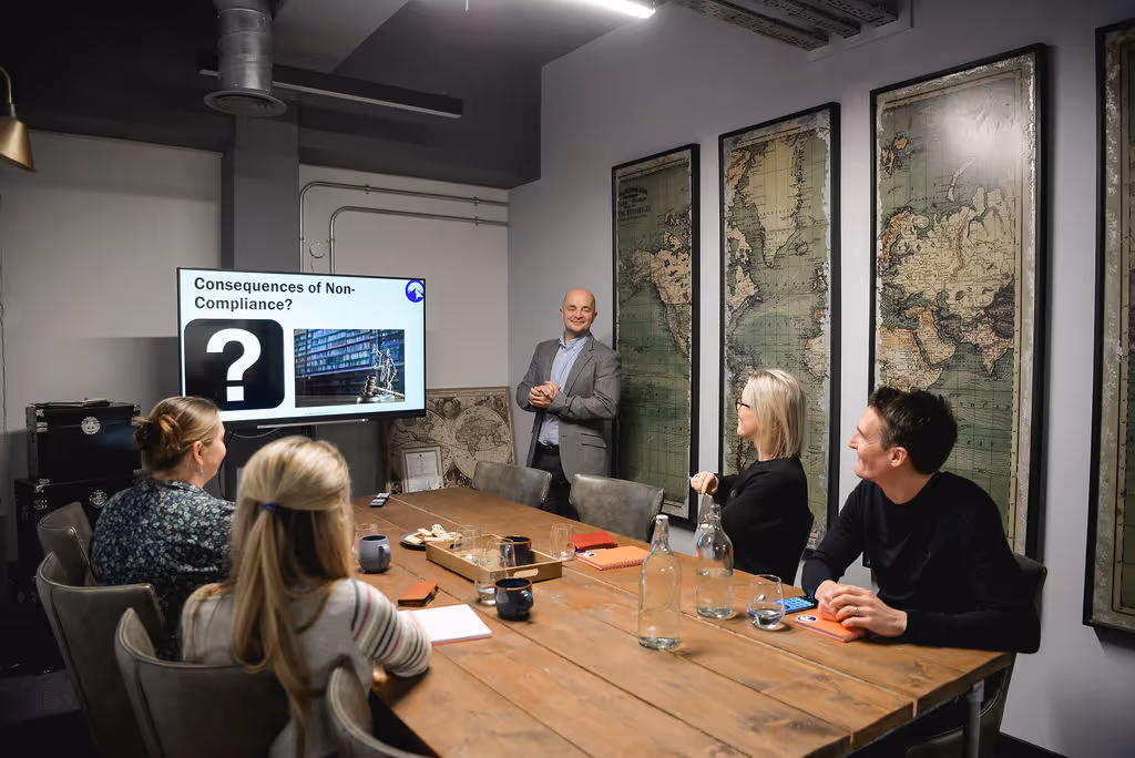 Group of people sat around a table looking towards a screen