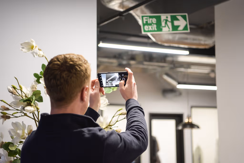 A man taking a picture of a fire exit sign
